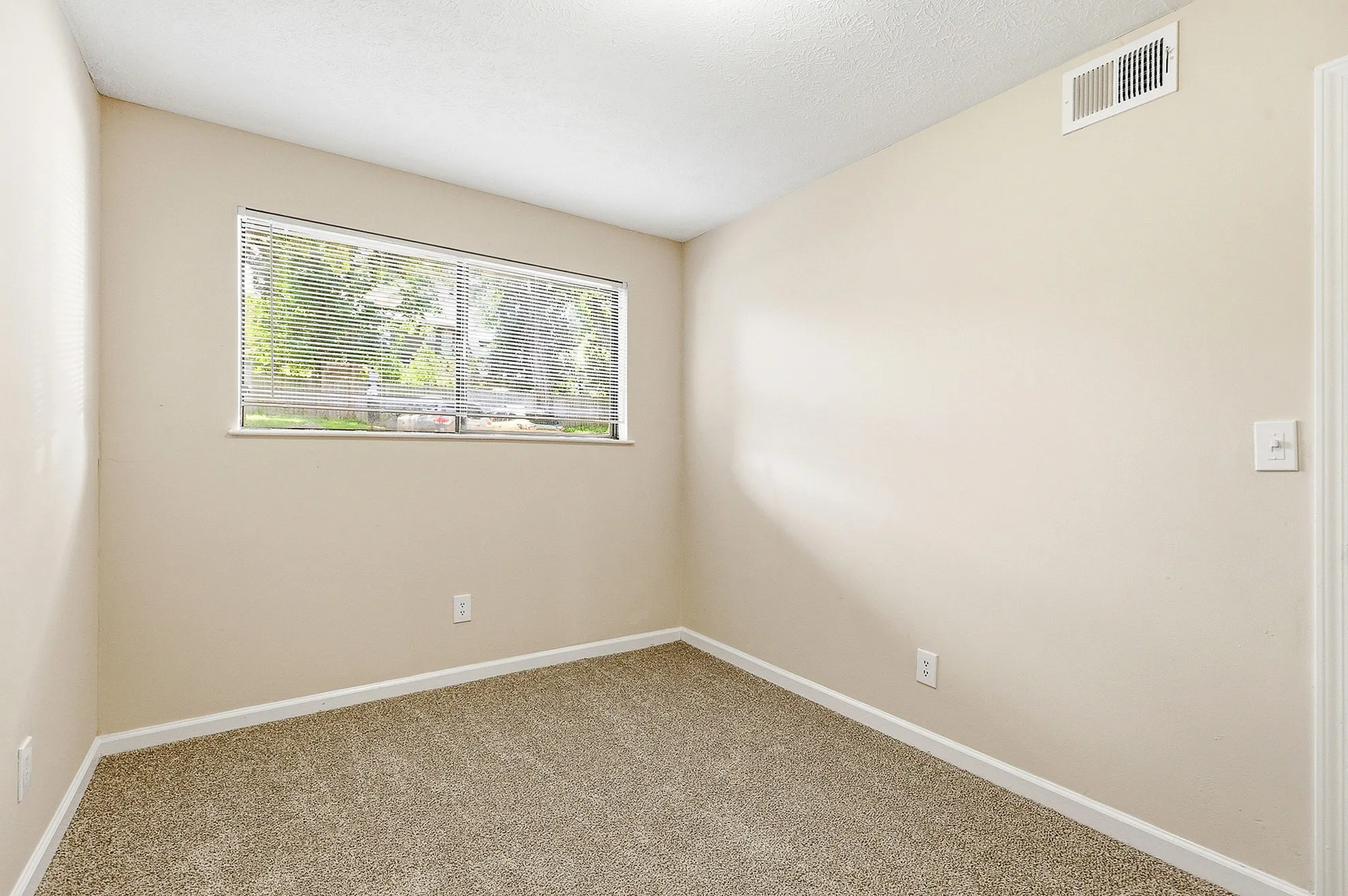 Bright and inviting bedroom featuring plush carpeting and a large window with serene outdoor views.