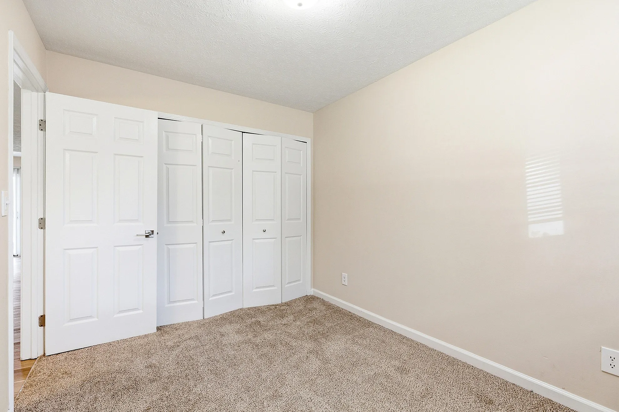 Bright and inviting bedroom with plush carpet and ample closet space featuring sleek white doors, creating a cozy retreat.