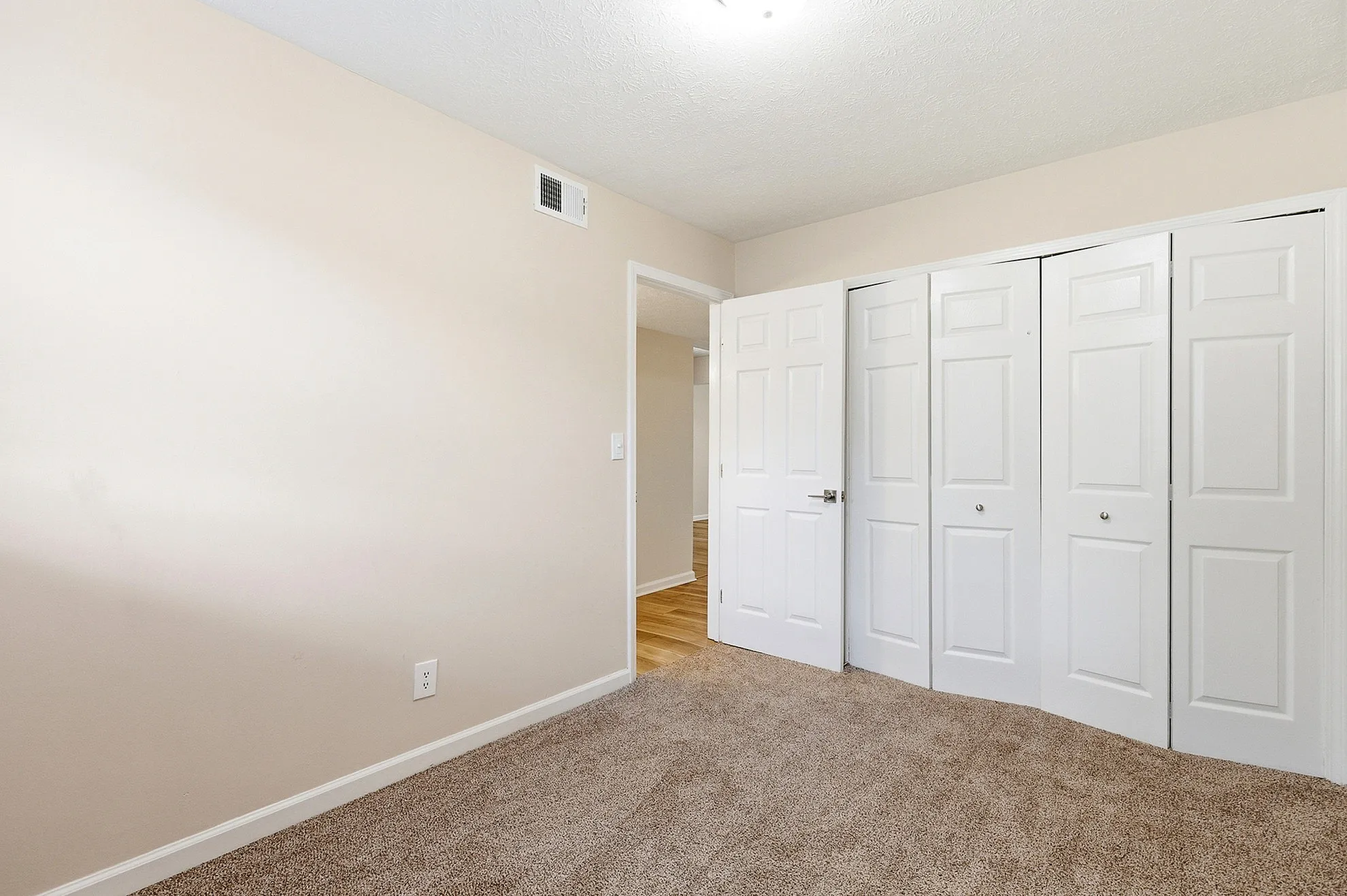 Bright and inviting bedroom with plush carpeting and spacious closets, perfect for modern living.