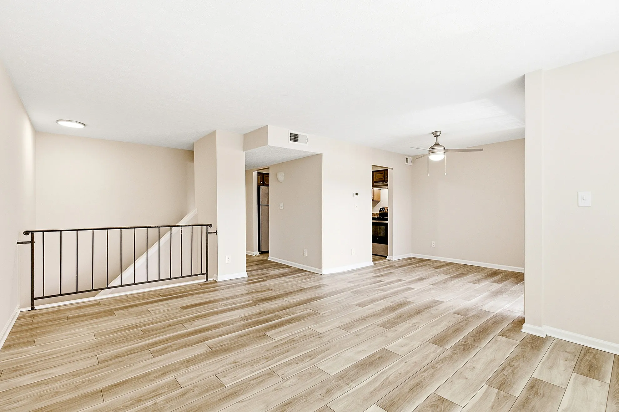 Bright and spacious open-plan living area with stylish wooden flooring and modern ceiling fan, ideal for comfortable living.