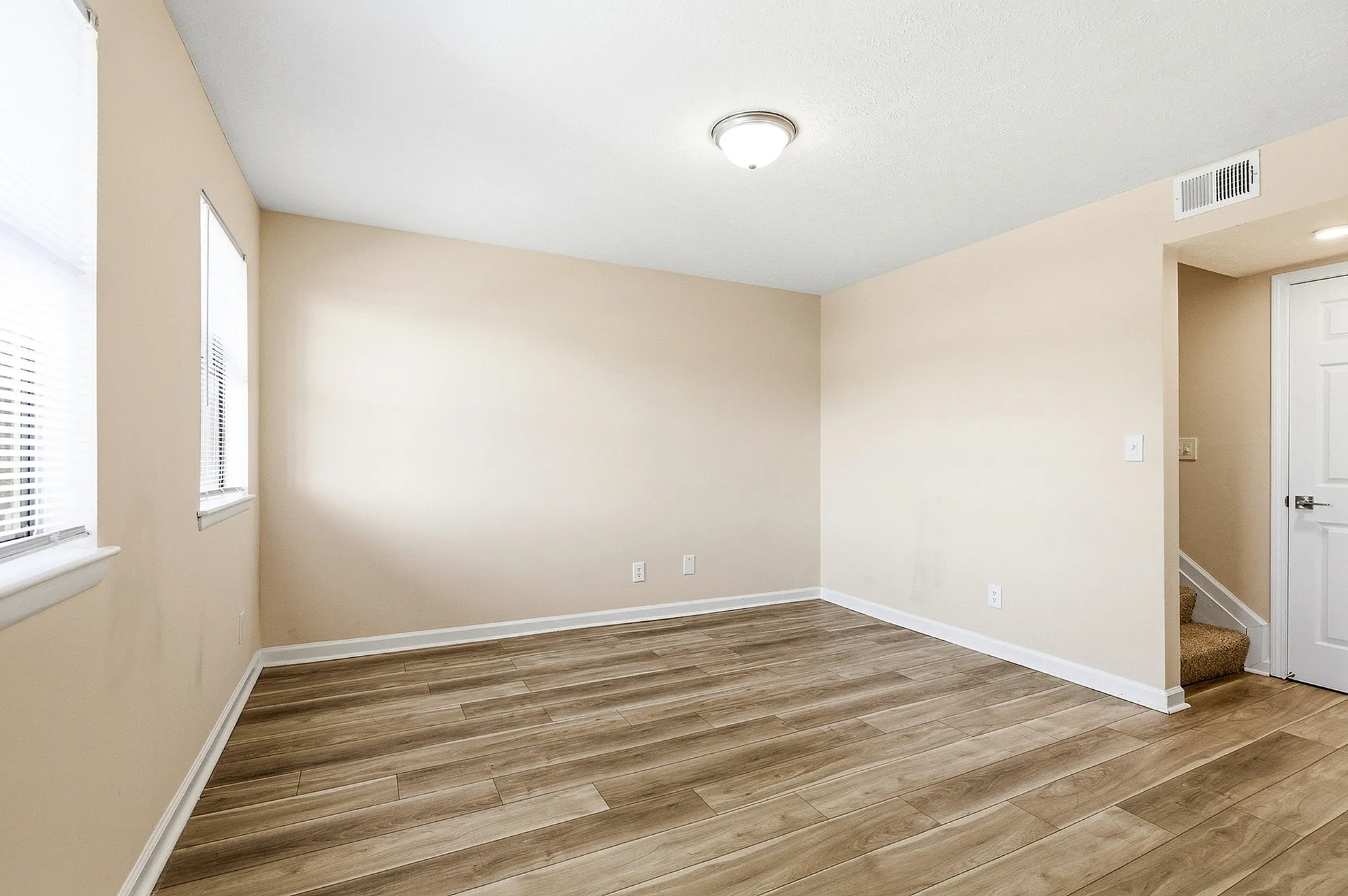 Bright, open room with elegant wood flooring and ample natural light from large windows.