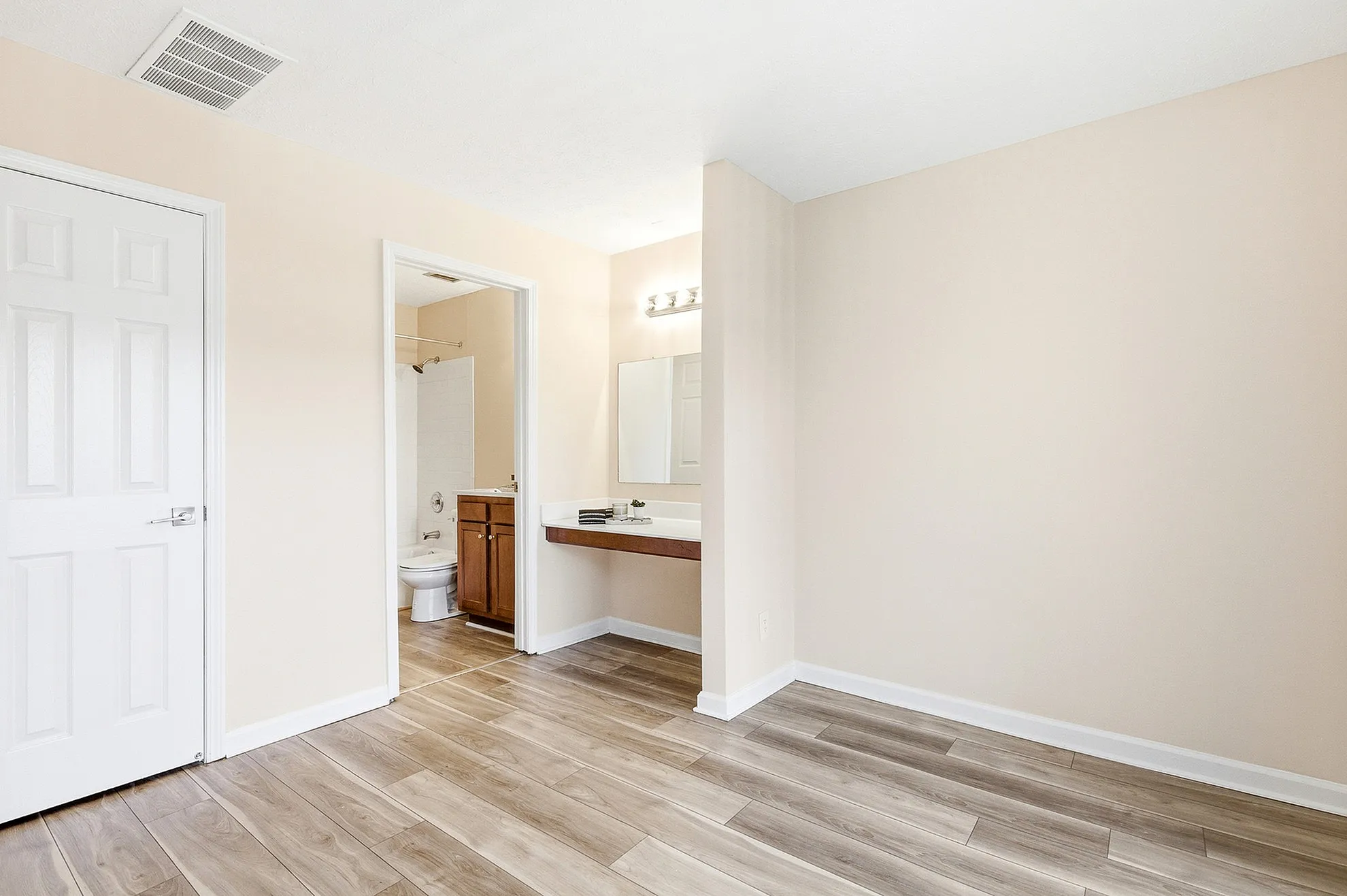 Bright, modern bathroom suite featuring sleek wooden flooring, a well-lit vanity area, and a stylish bathroom with elegant fixtures.