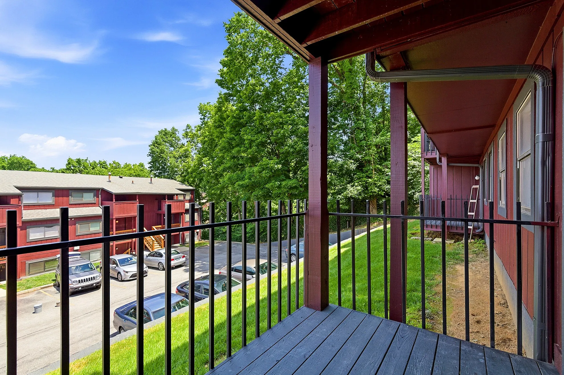 Inviting apartment balcony with stunning view of lush greenery and charming red-brick buildings, ideal for relaxing outdoors.