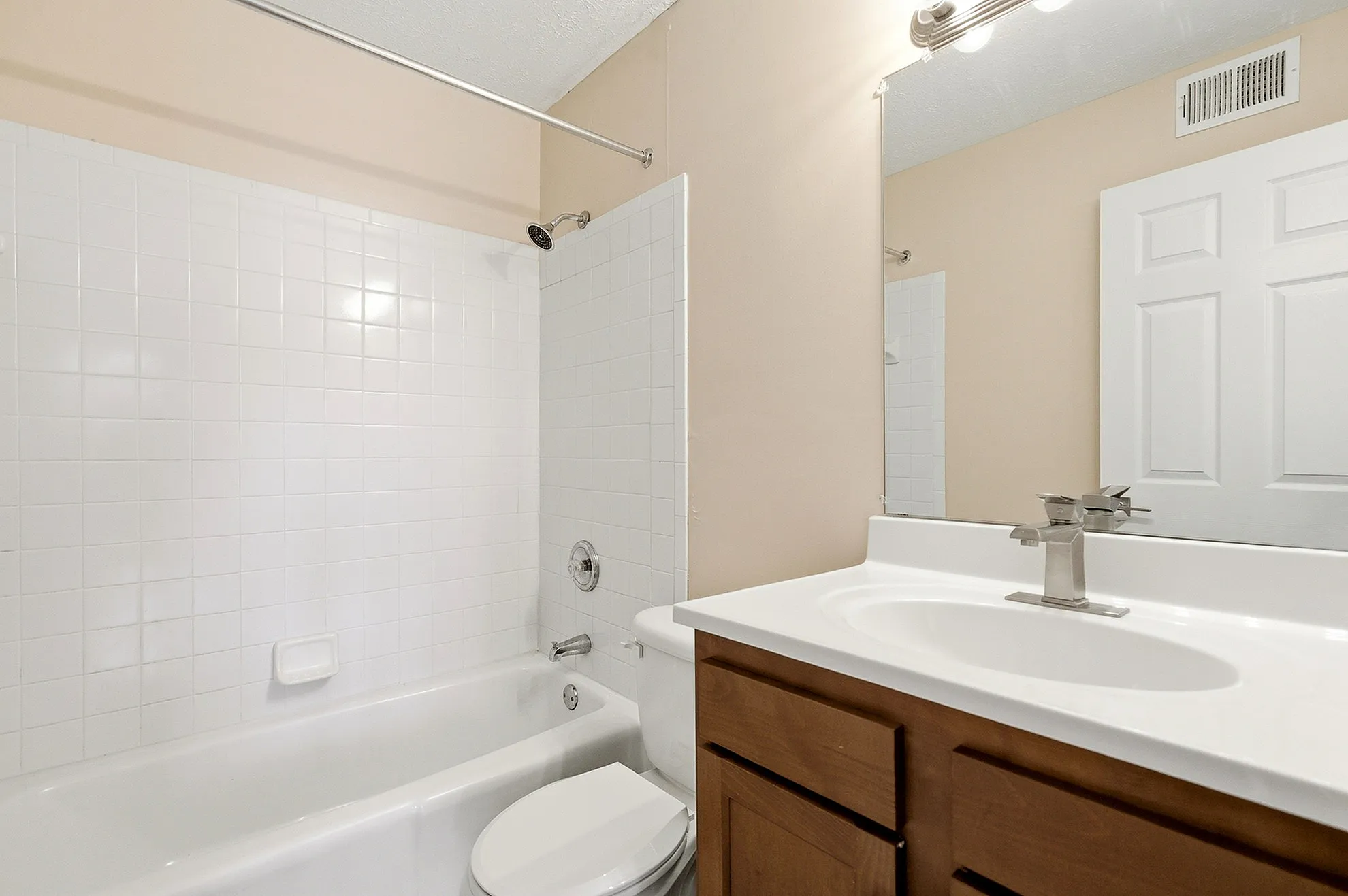 Bright, modern bathroom with sleek white tiles, stylish vanity, and tub-shower combo.