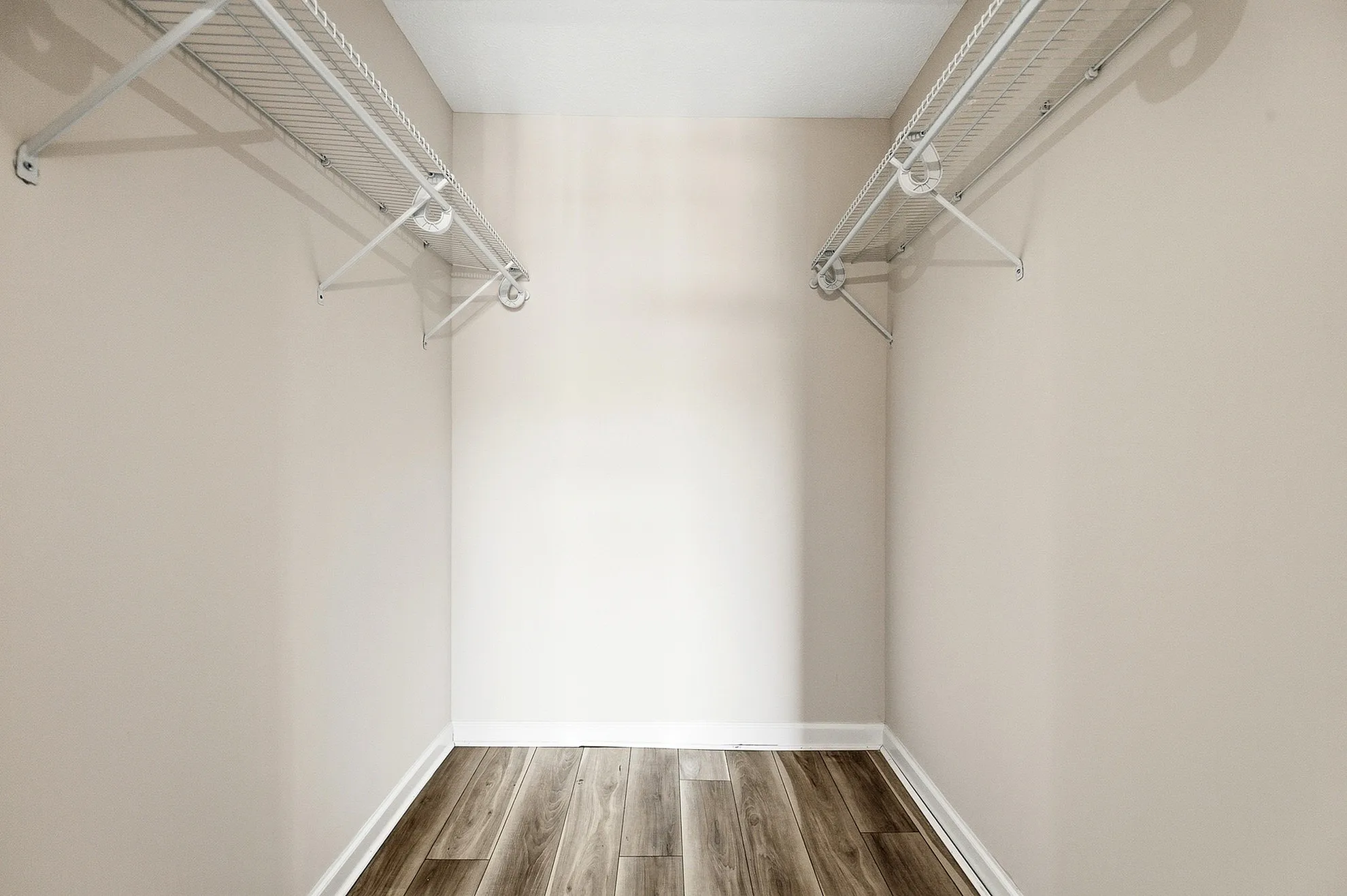Spacious walk-in closet with elegant wooden flooring and built-in shelving, perfect for ample storage.