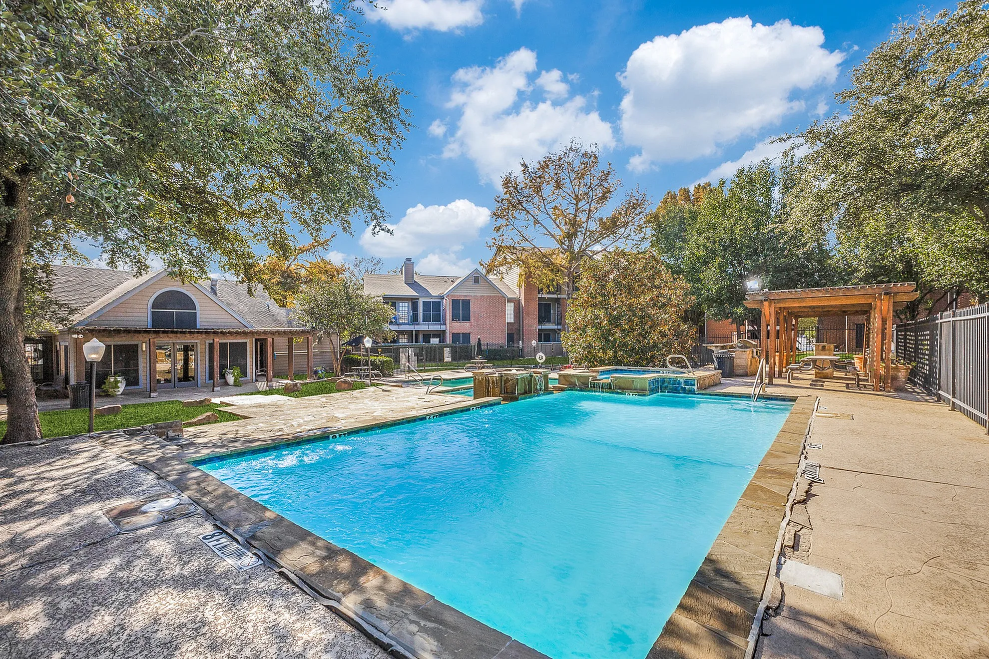 Inviting outdoor pool area surrounded by lush greenery and charming architecture, perfect for relaxation and social gatherings.