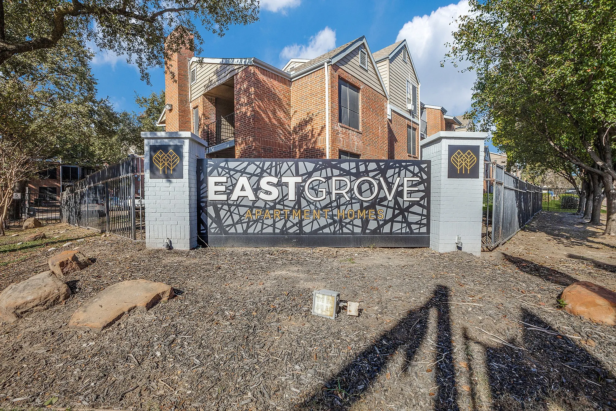 Charming brick architecture at East Grove Apartment Homes, nestled amidst lush greenery for serene living.