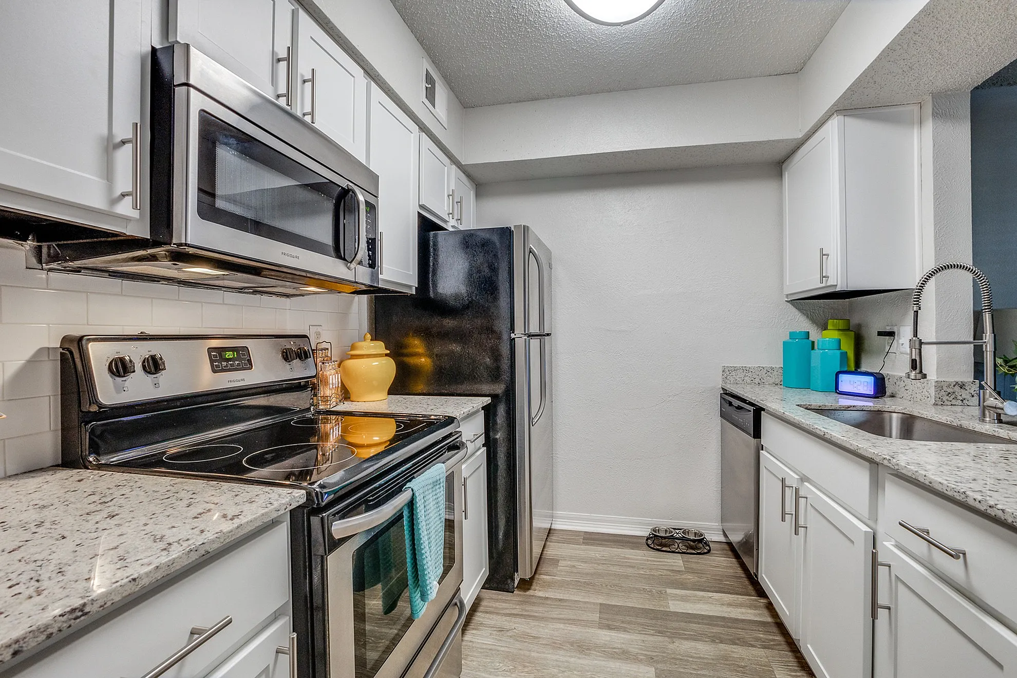 Modern kitchen with stainless steel appliances, elegant granite countertops, and stylish white cabinetry.