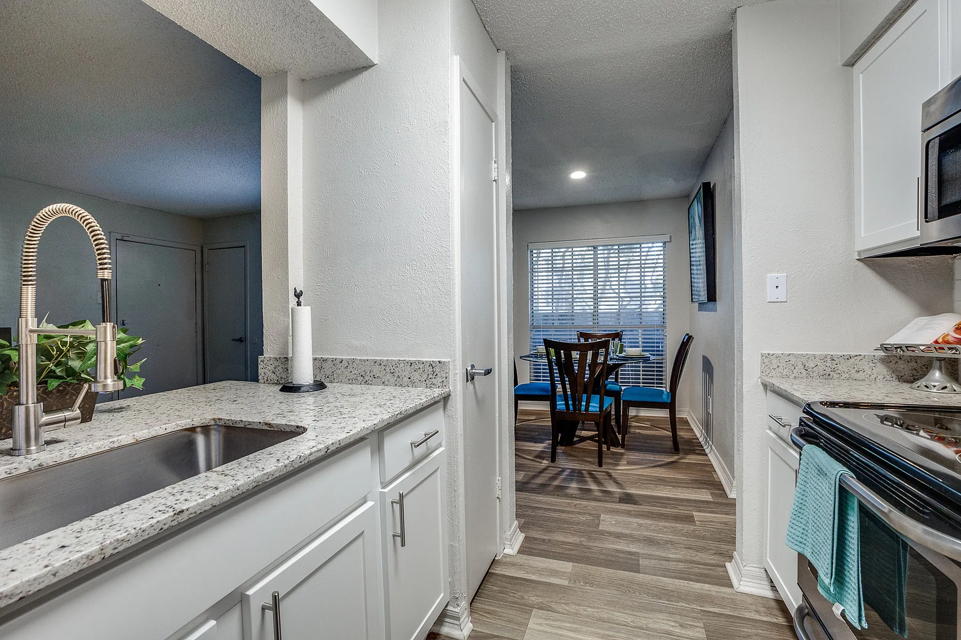 Elegant kitchen and dining area with modern granite countertops, sleek stainless steel appliances, and a cozy dining nook with large window providing natural light.