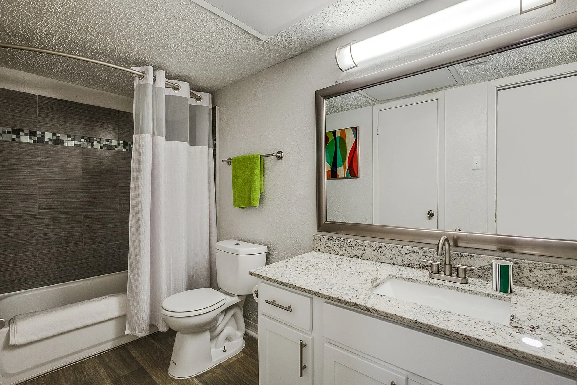 Contemporary bathroom with elegant granite countertop, stylish vanity, modern fixtures, and chic tiled shower.