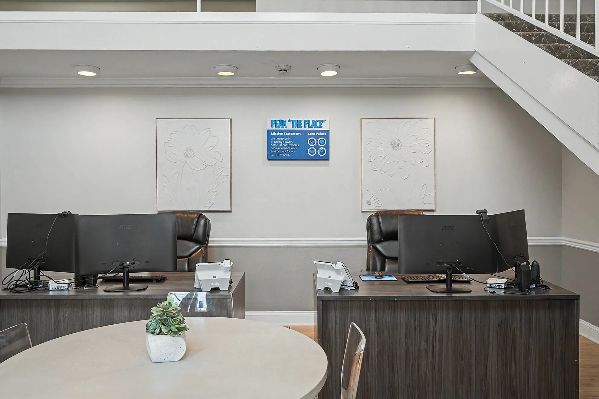Modern leasing office with sleek workstations, comfortable leather chairs, and stylish wall art adding to a welcoming atmosphere.