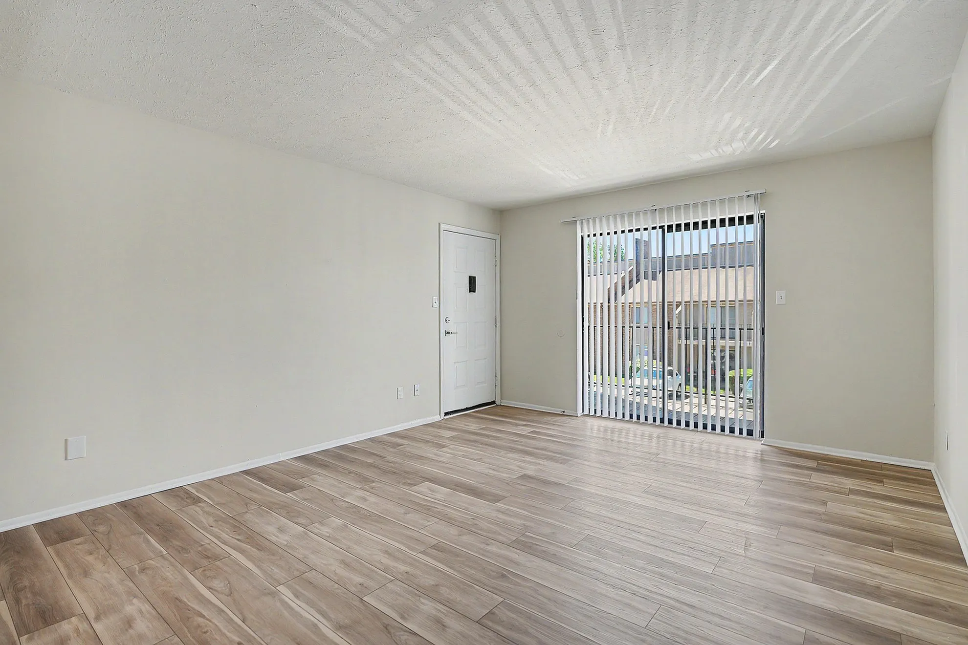 Bright and airy living space with elegant wooden flooring and large sliding glass doors opening to a scenic view.