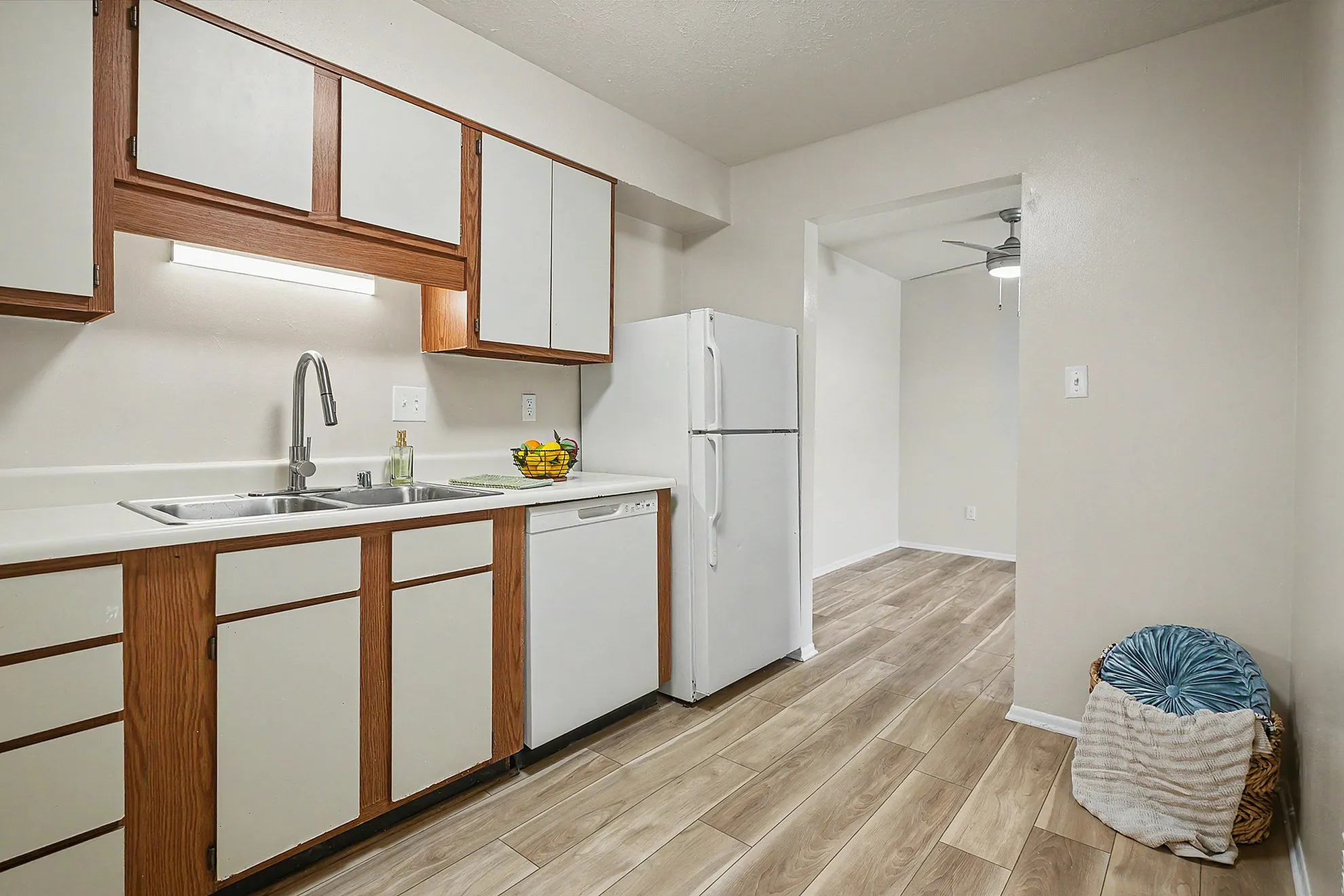 Charming kitchen with modern white cabinetry, sleek countertops, and wood-look flooring, leading into a bright dining area.