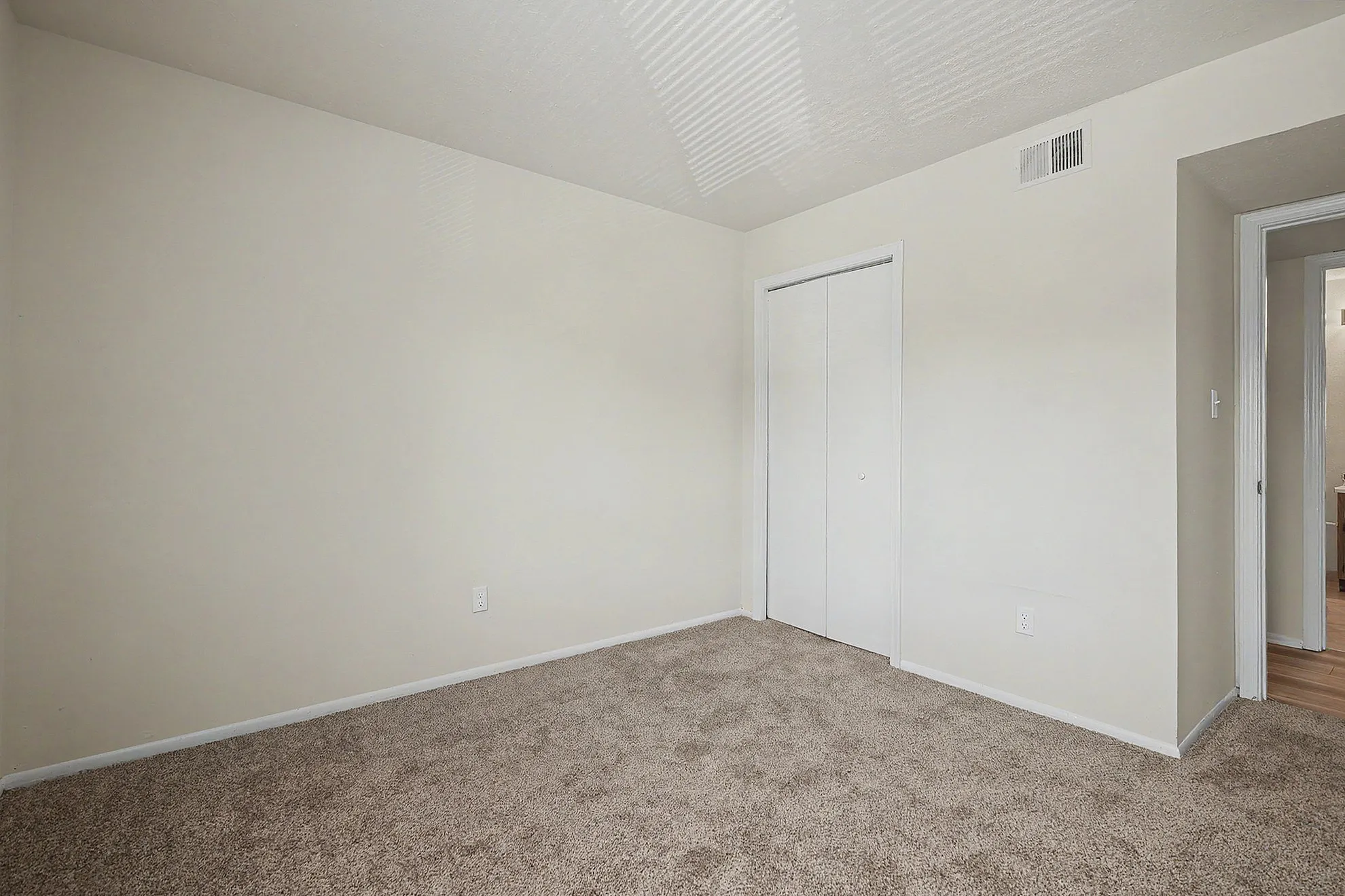 Bright and welcoming bedroom with plush carpet, pristine white walls, and ample closet space for modern living.