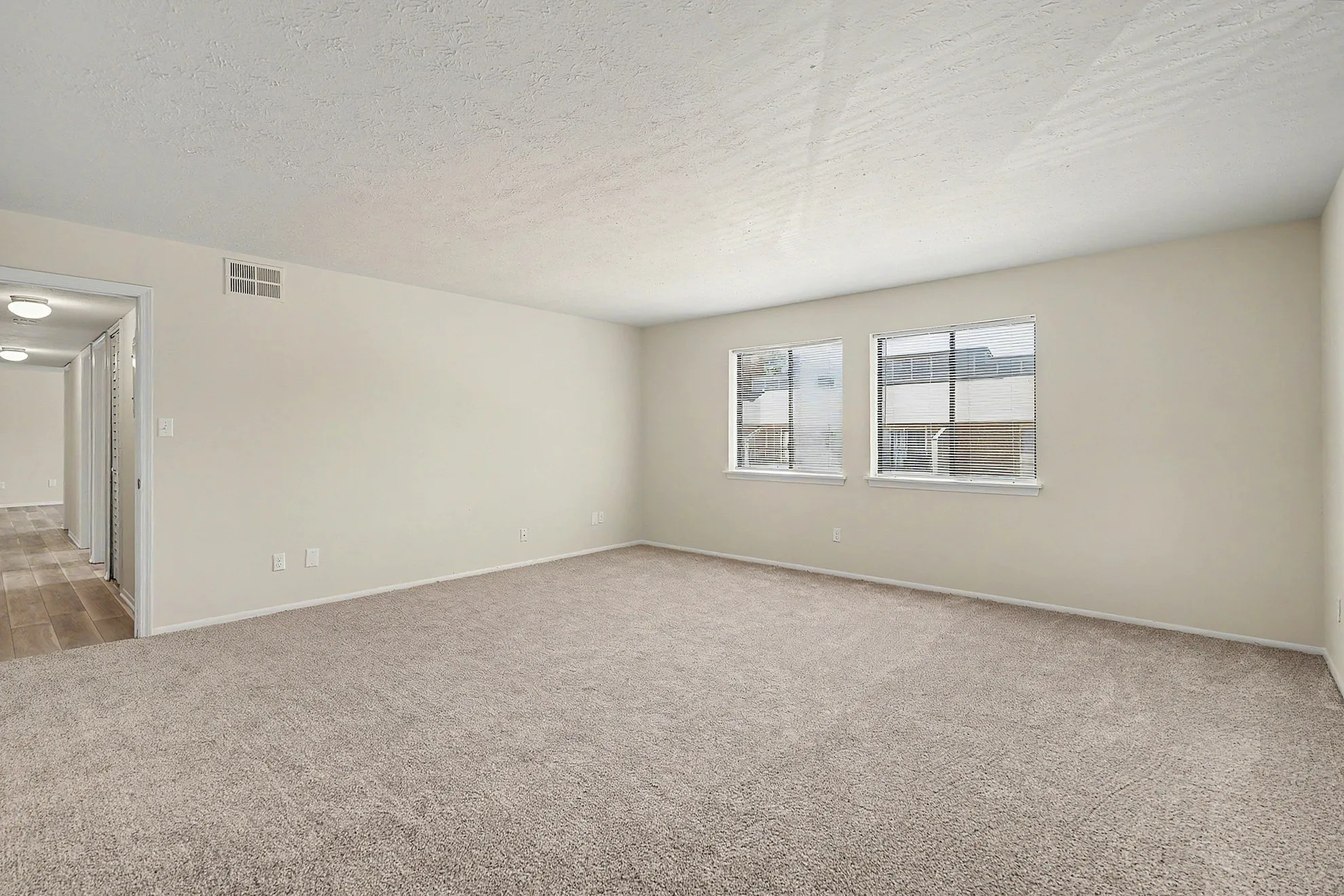 Bright and spacious carpeted room with large windows and ample natural light, perfect for a cozy and inviting living space.