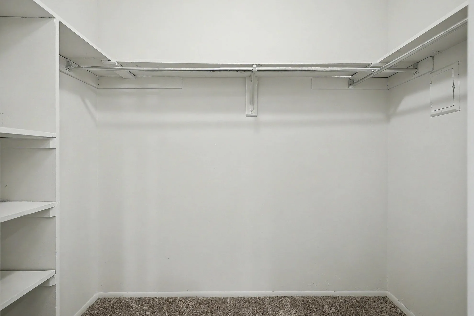 Spacious walk-in closet with built-in shelving and ample hanging space, perfect for organized storage.