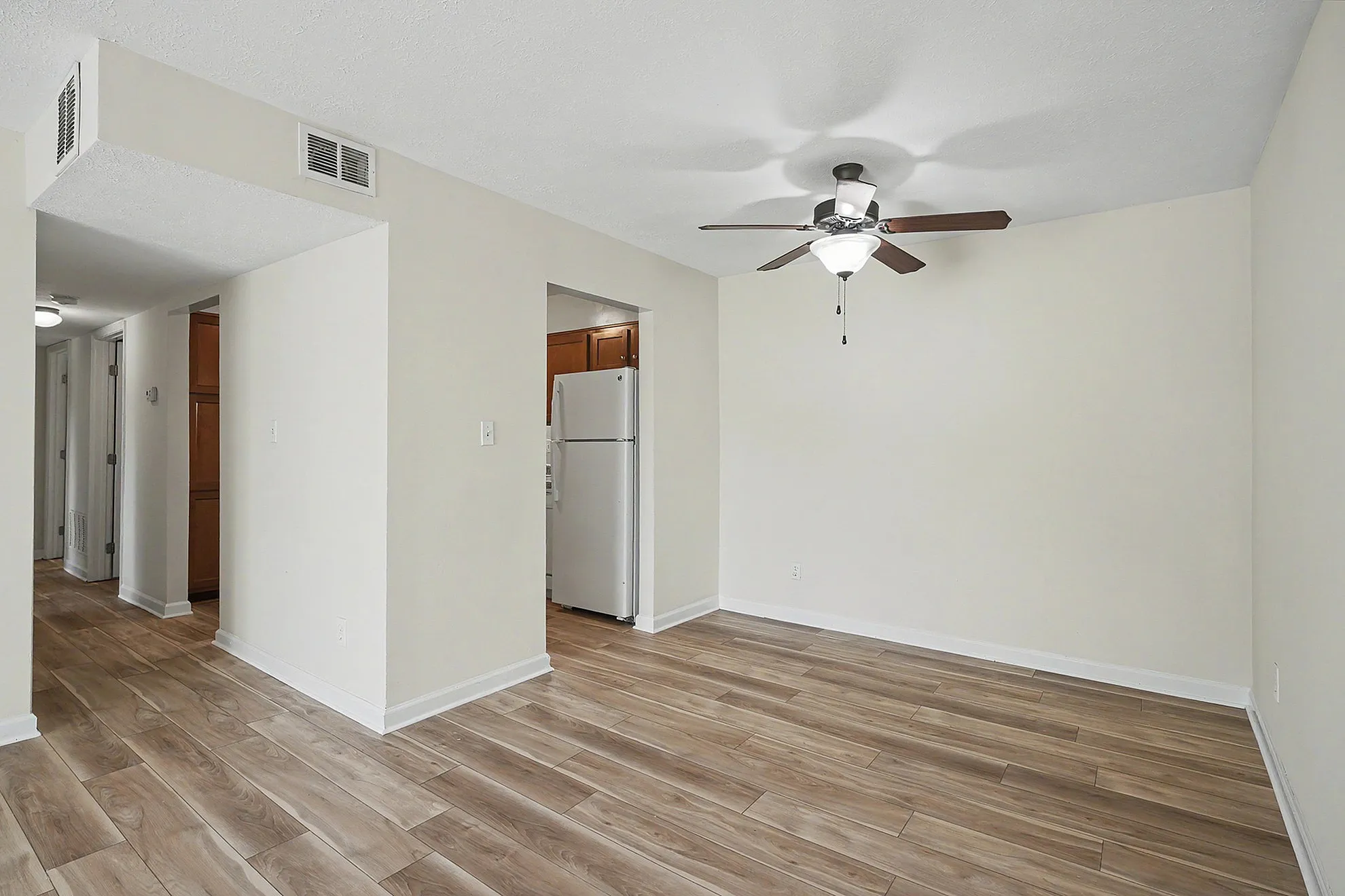 Inviting open-plan area with elegant wood flooring, ceiling fan, and sightlines into a cozy kitchen, perfect for modern living.