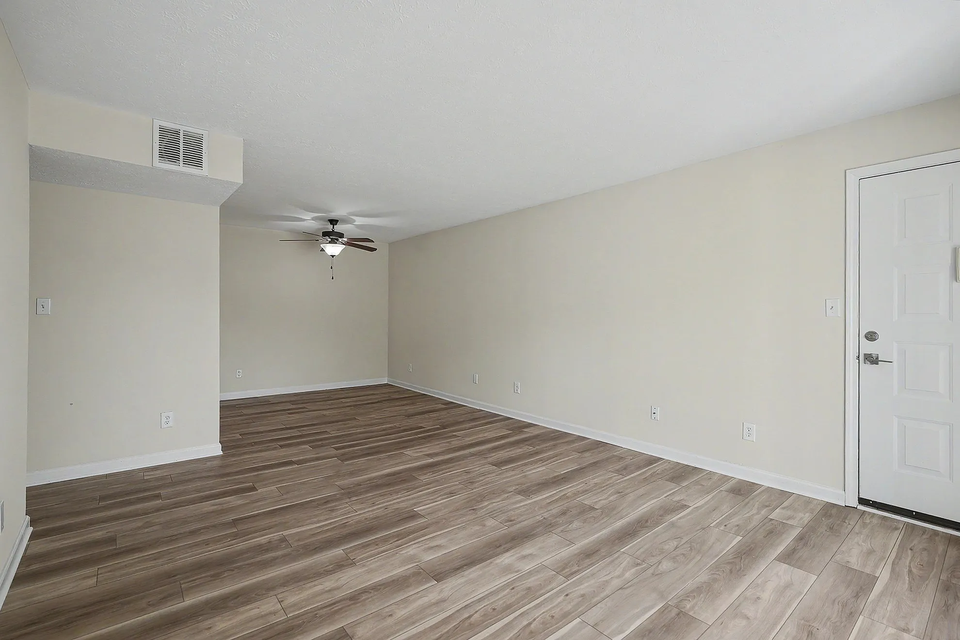Bright and airy apartment space with elegant wood flooring and a modern ceiling fan, perfect for a cozy living area.