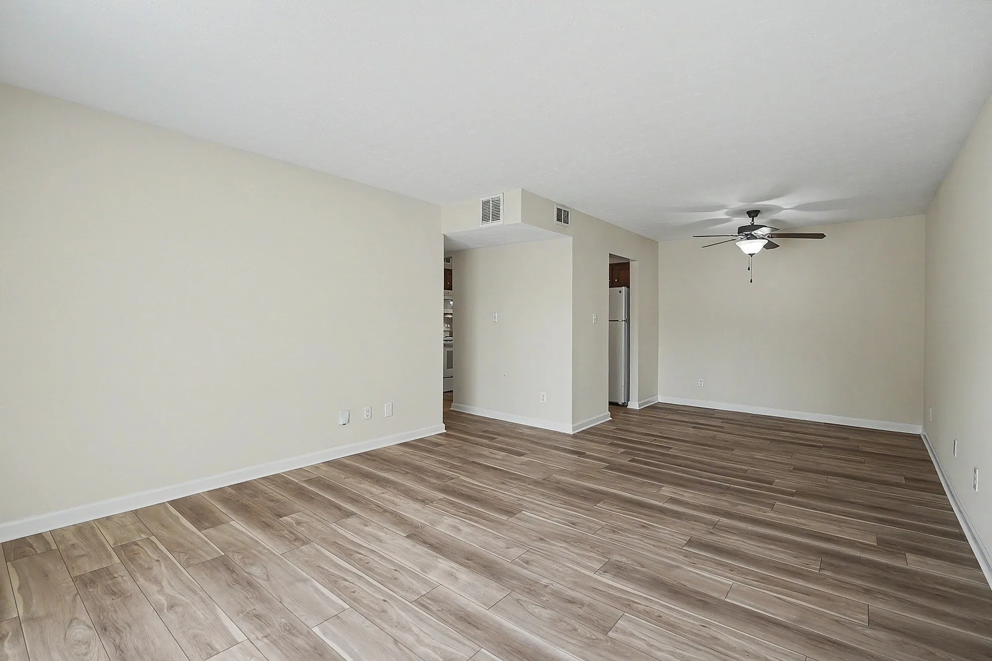 Spacious living room with elegant wood flooring and a ceiling fan, perfect for a comfortable and stylish home.
