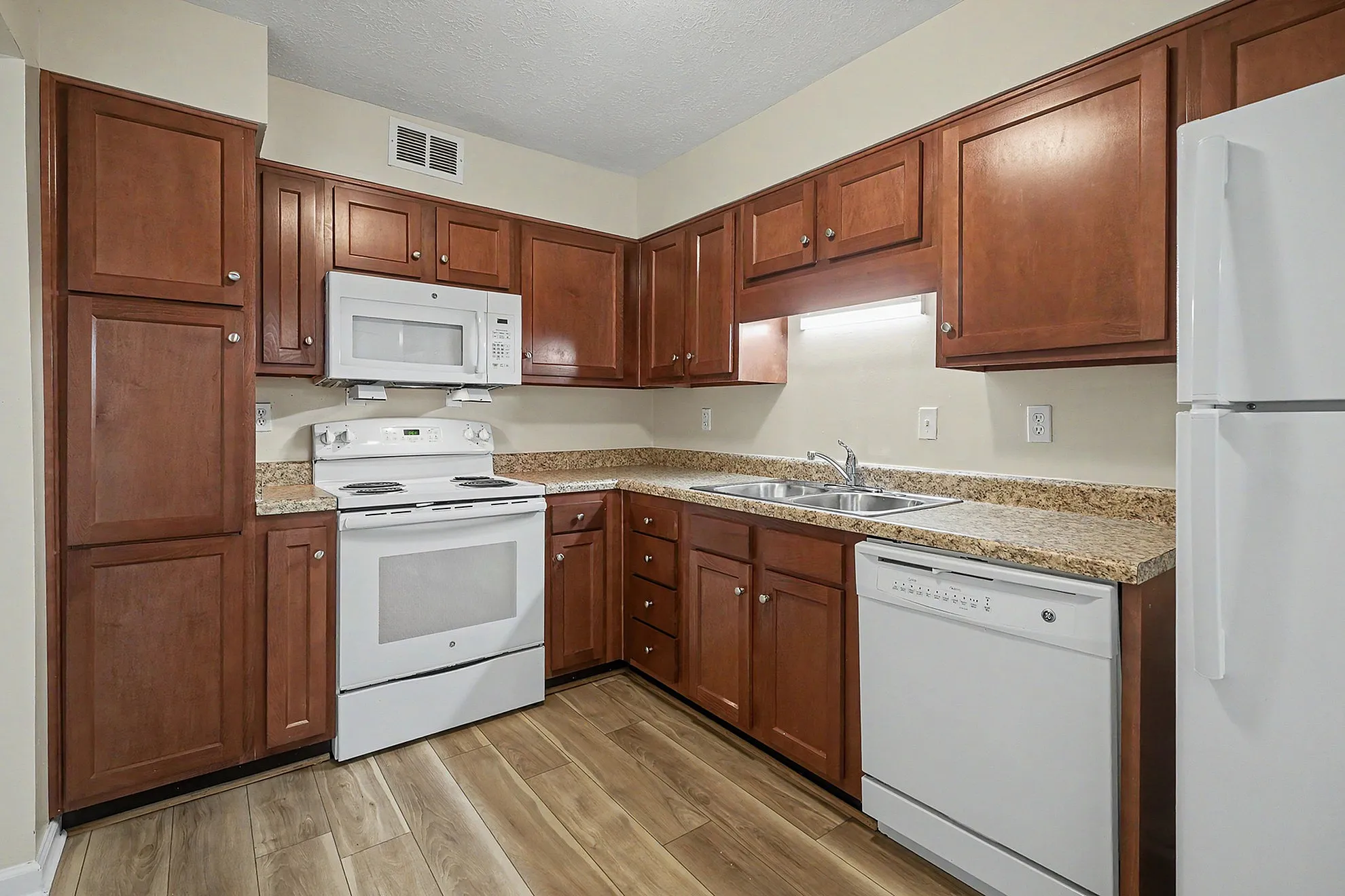 Charming kitchen with warm wood cabinetry, modern appliances, and elegant granite countertops for a cozy cooking experience.