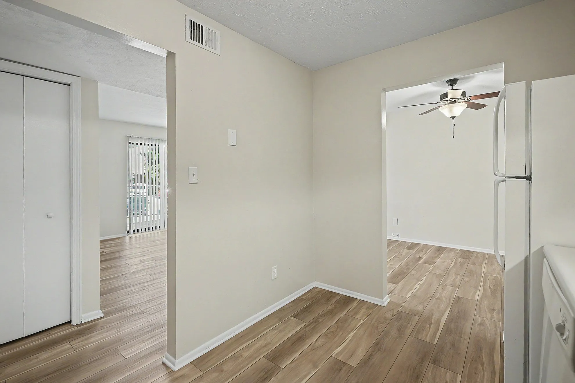 Modern apartment interior showcasing elegant hardwood floors, bright natural lighting, and a ceiling fan for added comfort.