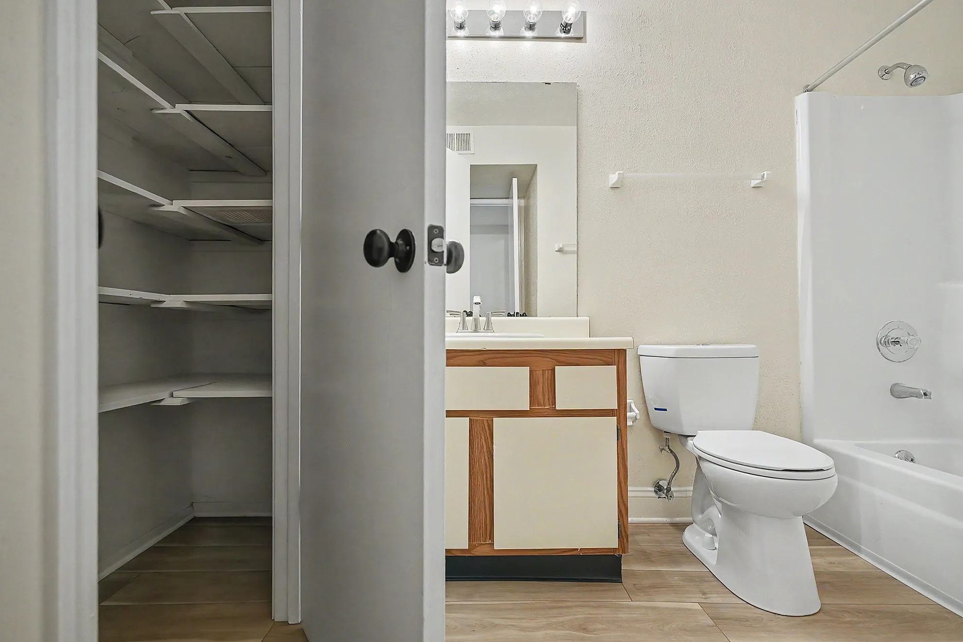 Modern bathroom featuring bright vanity, sleek shower-tub combo, and spacious built-in shelving.