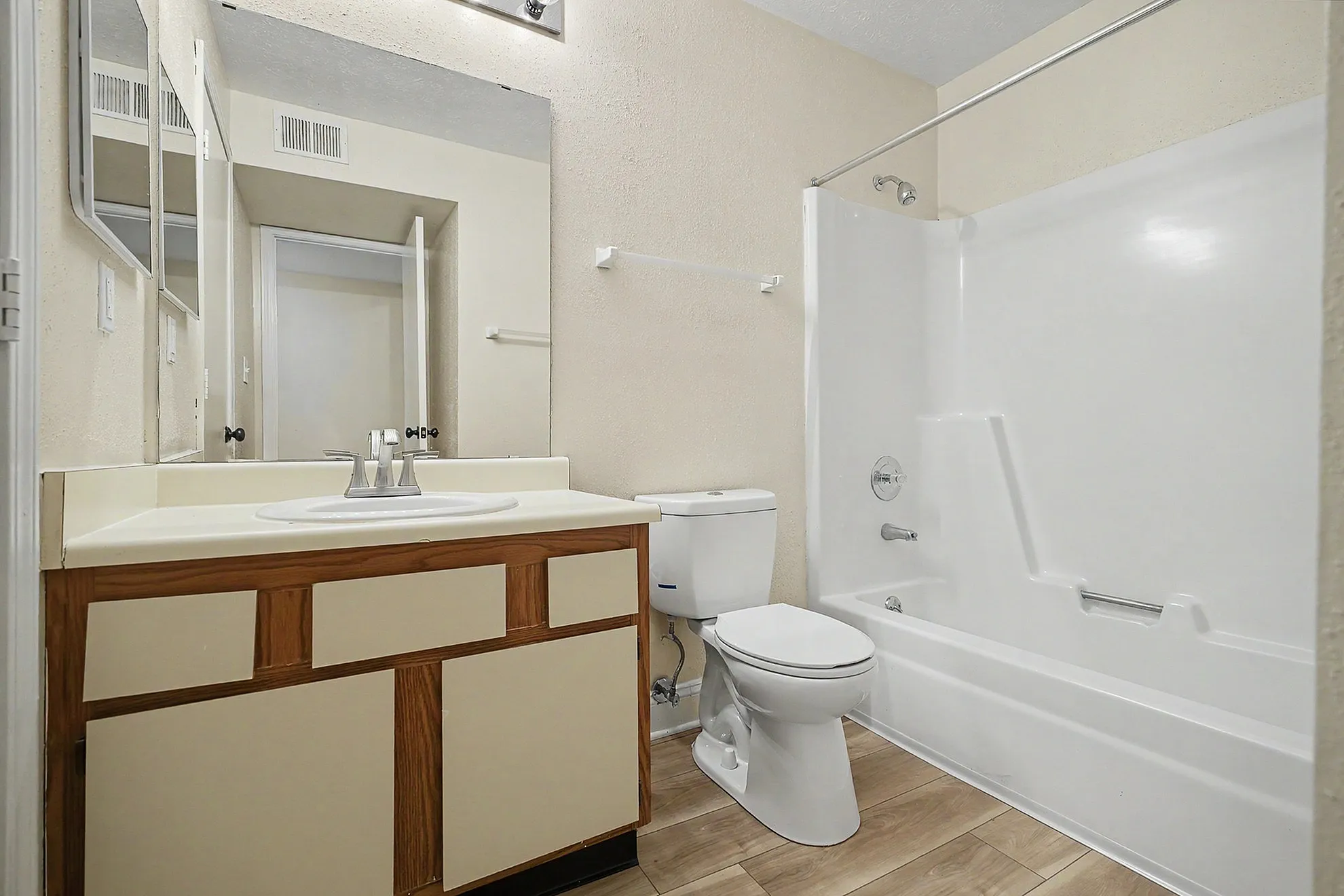Bright and inviting bathroom featuring a pristine bathtub, modern sink, and elegant wood-accented cabinetry.