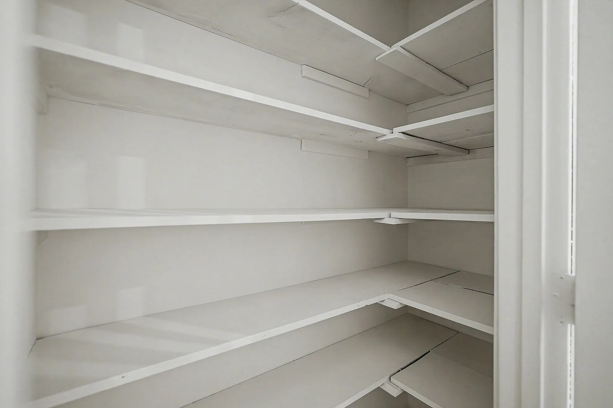 Spacious white pantry with multiple shelves, ideal for organized storage and maximizing space.