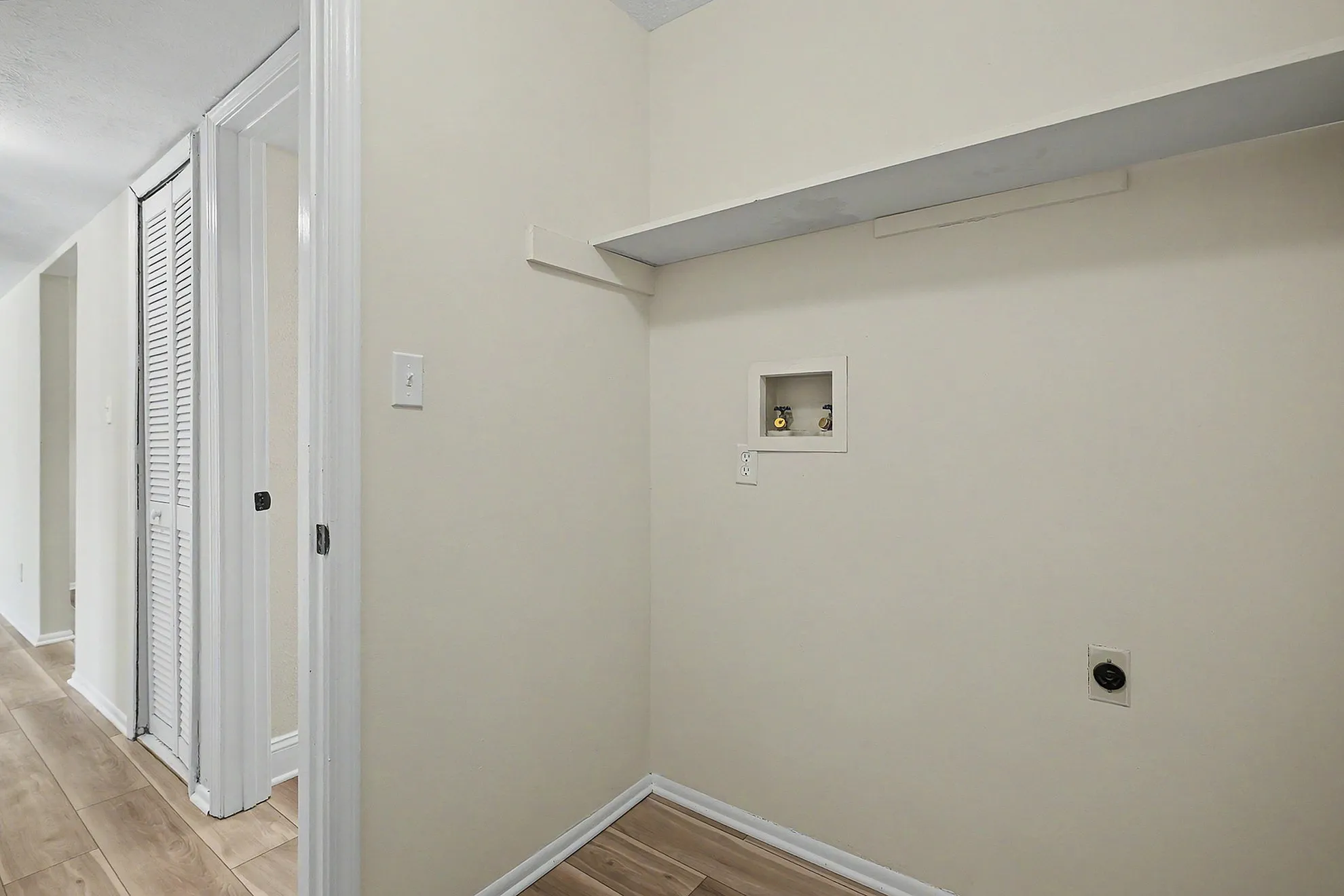Elegant laundry space with built-in shelving and modern hookups, perfect for a compact and efficient apartment setup.