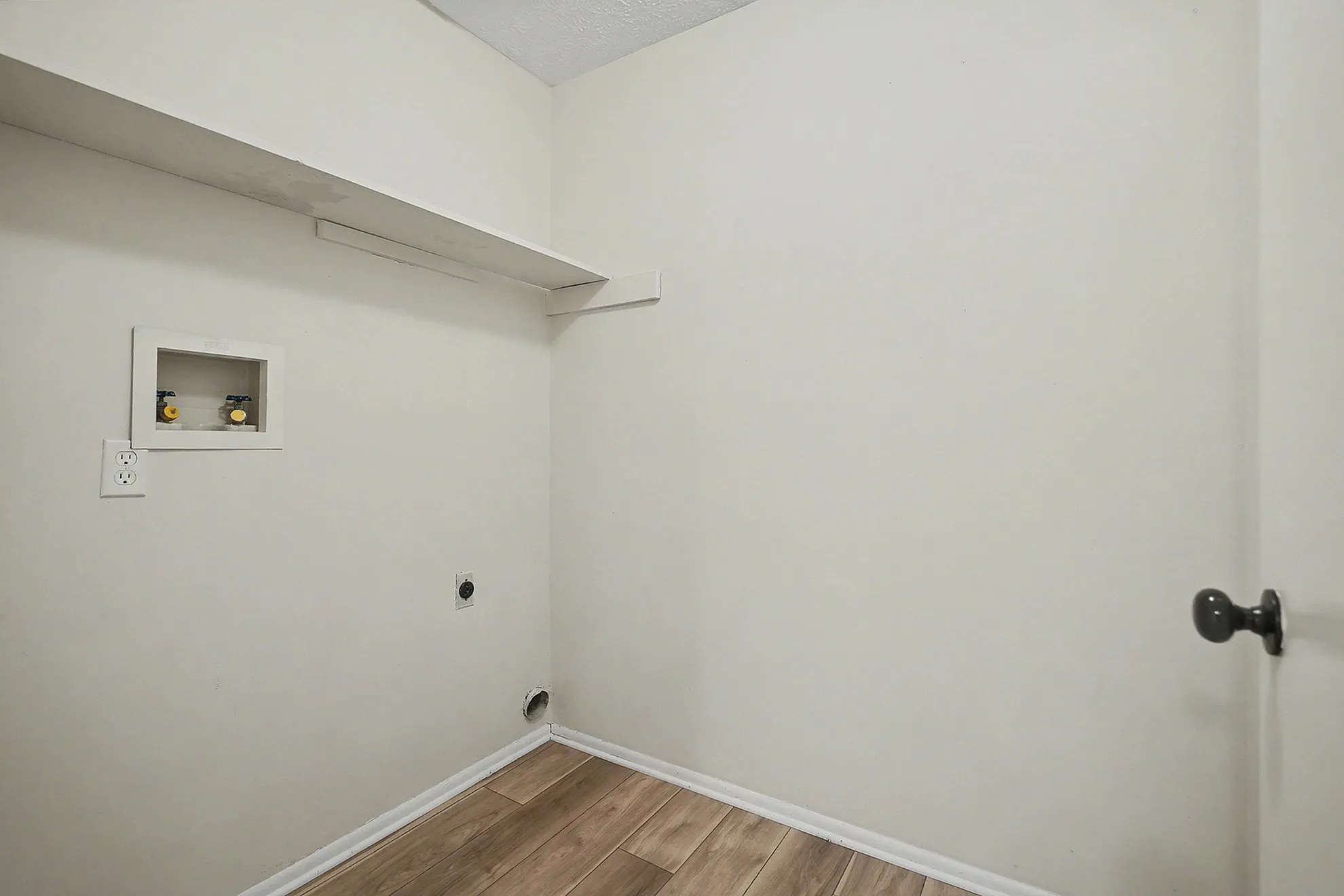 Bright utility room with sleek wooden flooring, perfect for laundry and storage solutions.