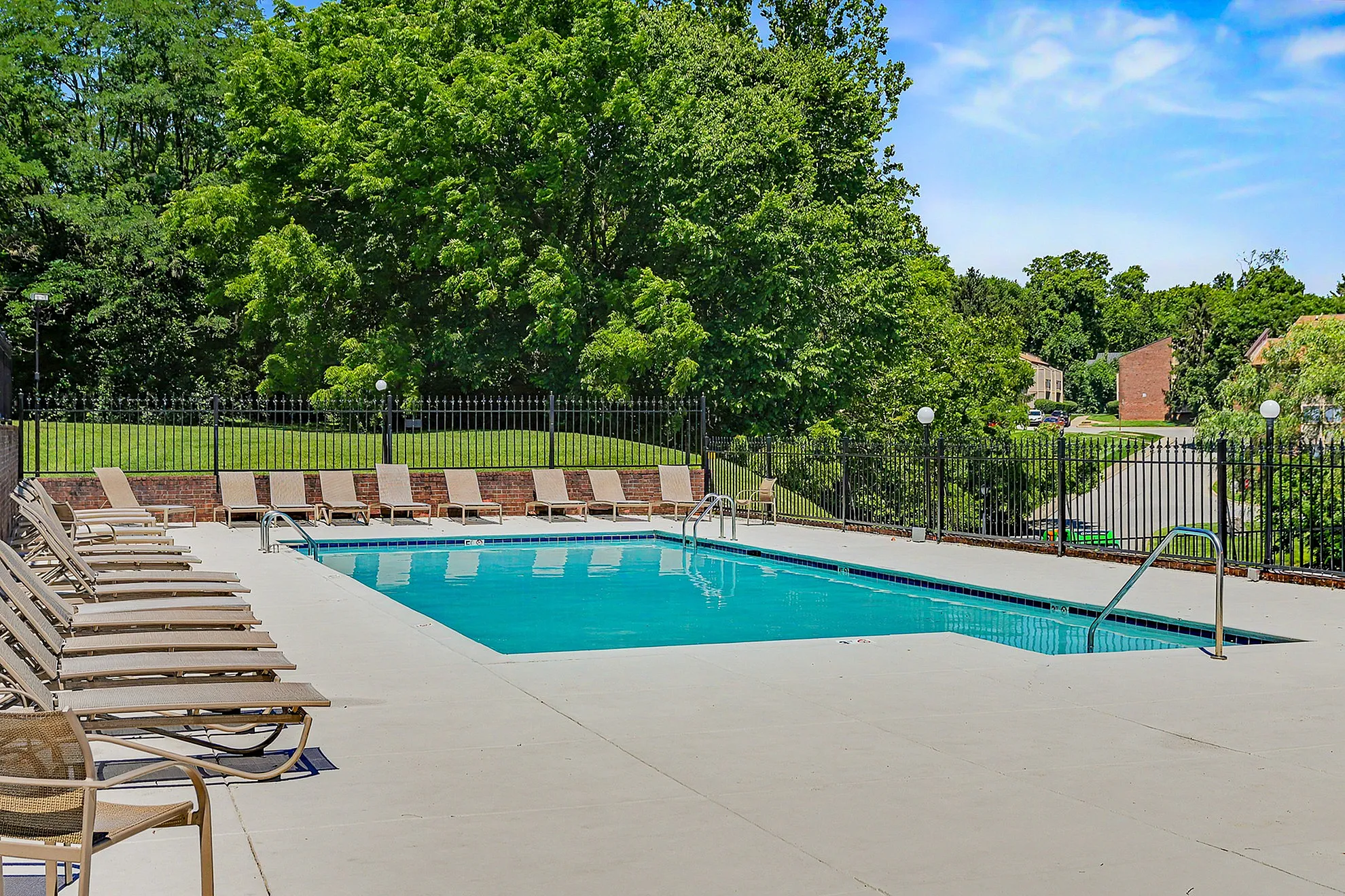 Inviting outdoor swimming pool surrounded by lush greenery and ample lounge chairs, perfect for relaxation and sunbathing.