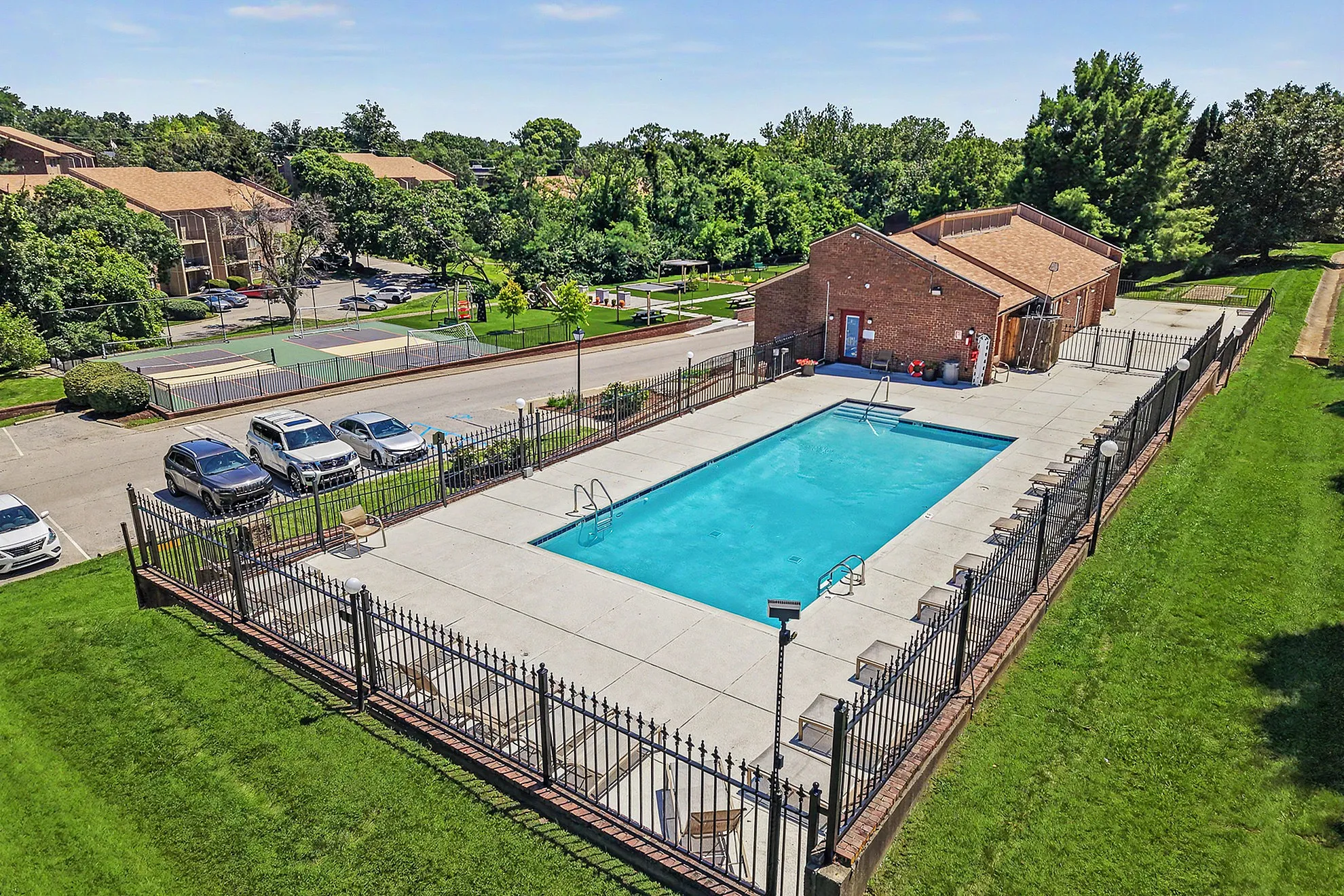 Inviting apartment amenities with a sparkling outdoor pool, lush green surroundings, and modern recreational facilities.