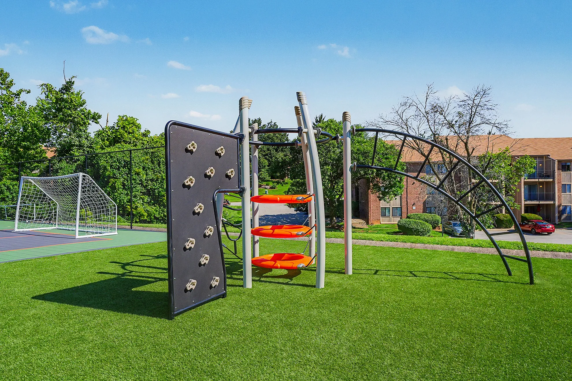 Inviting outdoor playground with a climbing wall and play equipment set on lush green grass, perfect for family fun and community living.