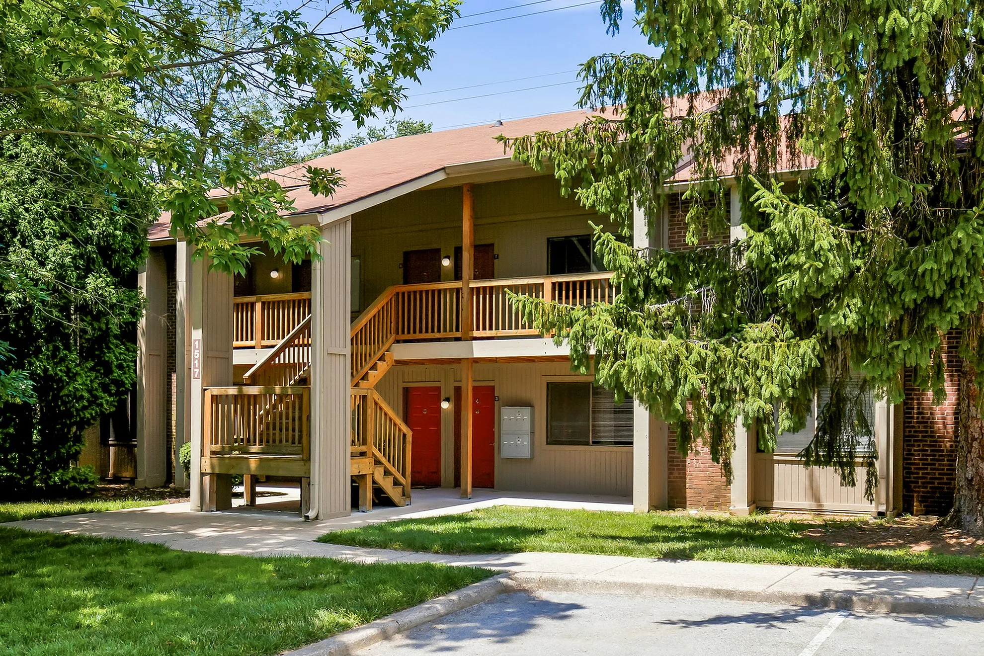 Charming apartment building with a welcoming wooden staircase, lush greenery, and a serene atmosphere.