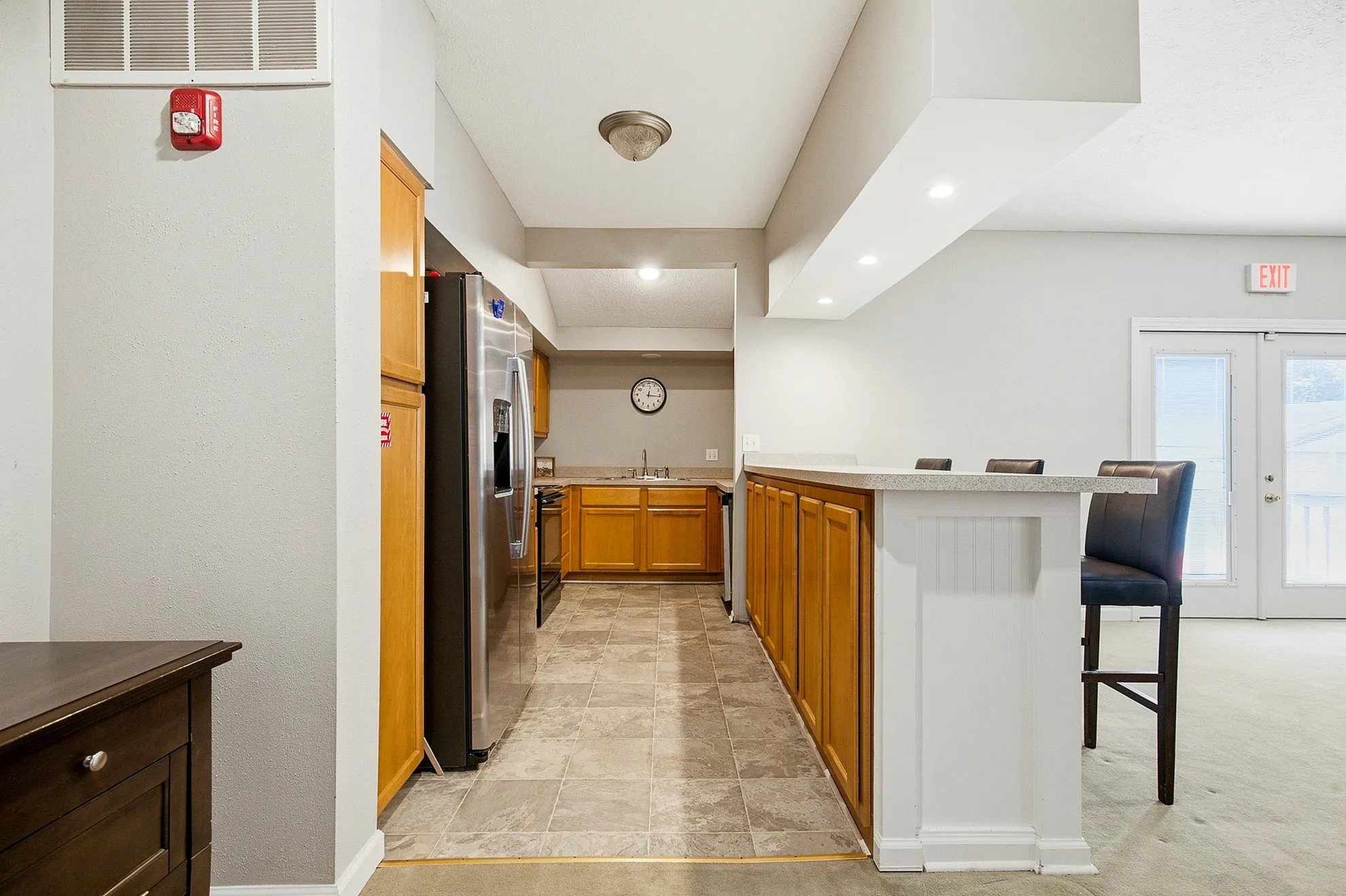 Bright, modern kitchen with sleek stainless steel appliances, cozy breakfast bar, and warm wooden cabinetry.