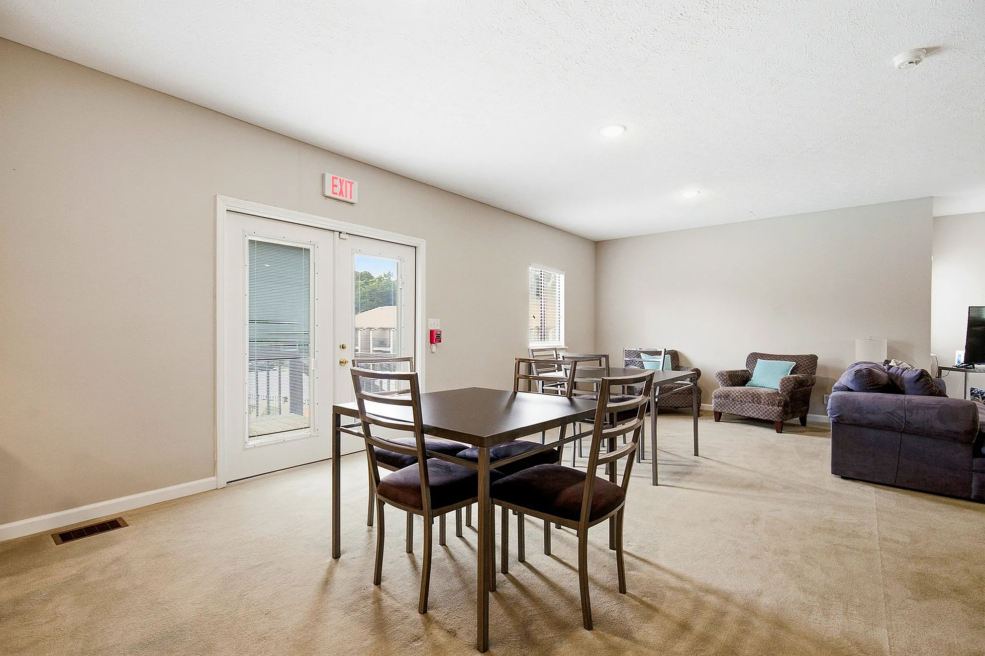 Spacious and inviting living area with modern dining setup and cozy seating, featuring abundant natural light through large windows.