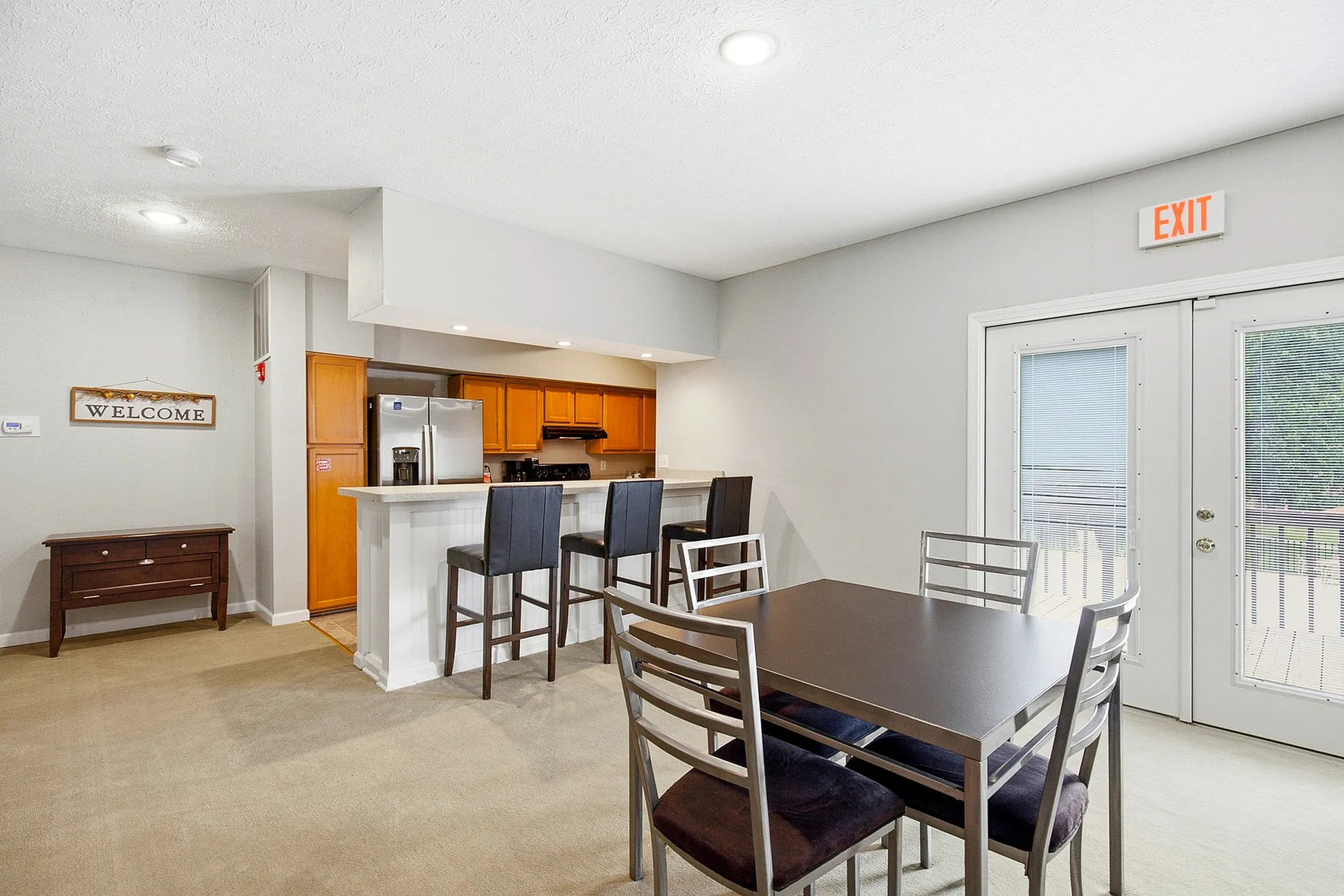 Inviting open-plan kitchen and dining area with modern appliances, high-top breakfast bar, and a sleek dining table, perfect for social gatherings.