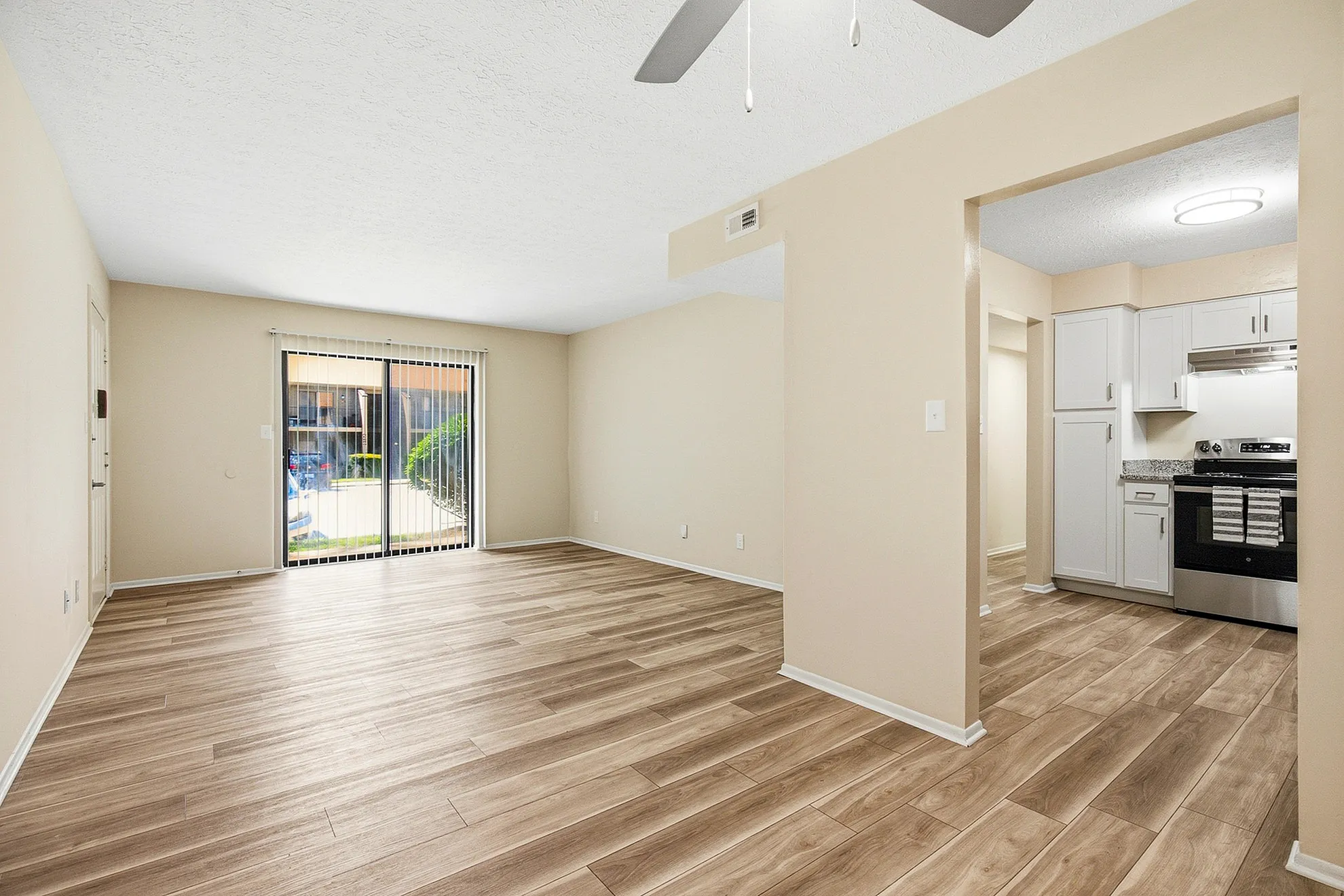 Inviting open-concept living space with stylish wood flooring, adjacent to a modern kitchen with sleek cabinets and stainless steel appliances.