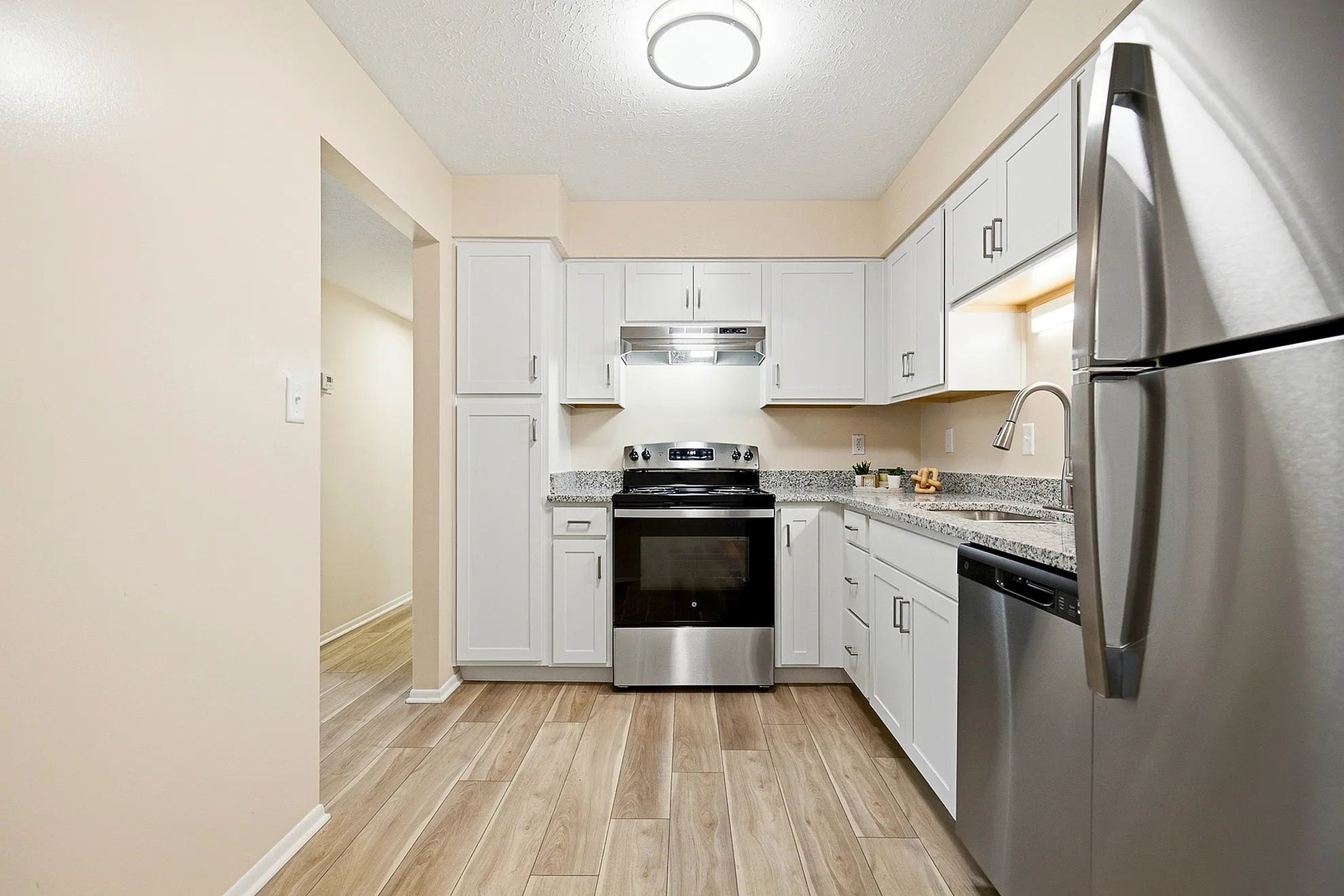 Modern kitchen featuring sleek stainless steel appliances, granite countertops, and elegant white cabinetry.