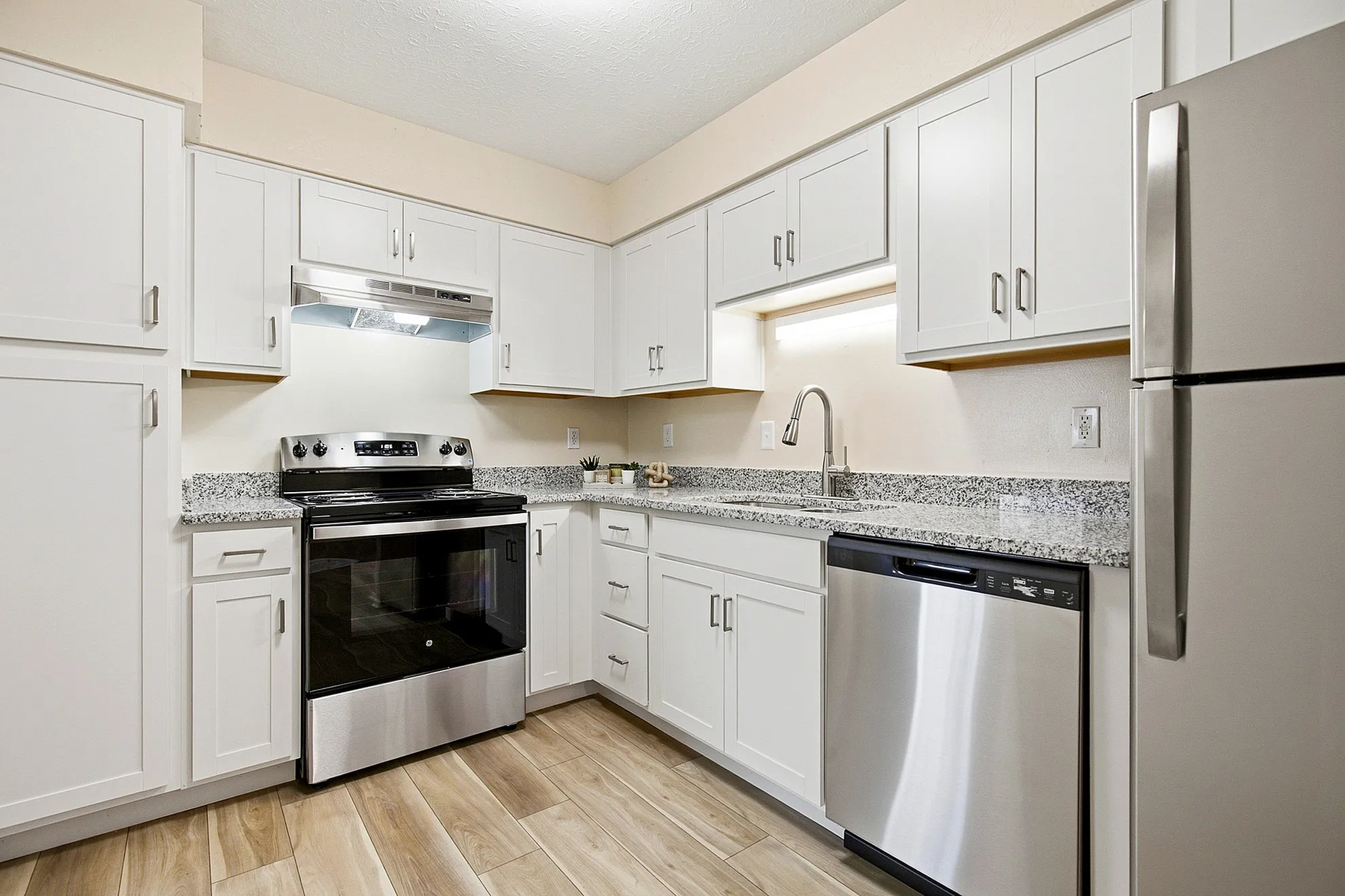 Modern kitchen with sleek stainless steel appliances, elegant white cabinets, and granite countertops, creating a stylish and functional space.