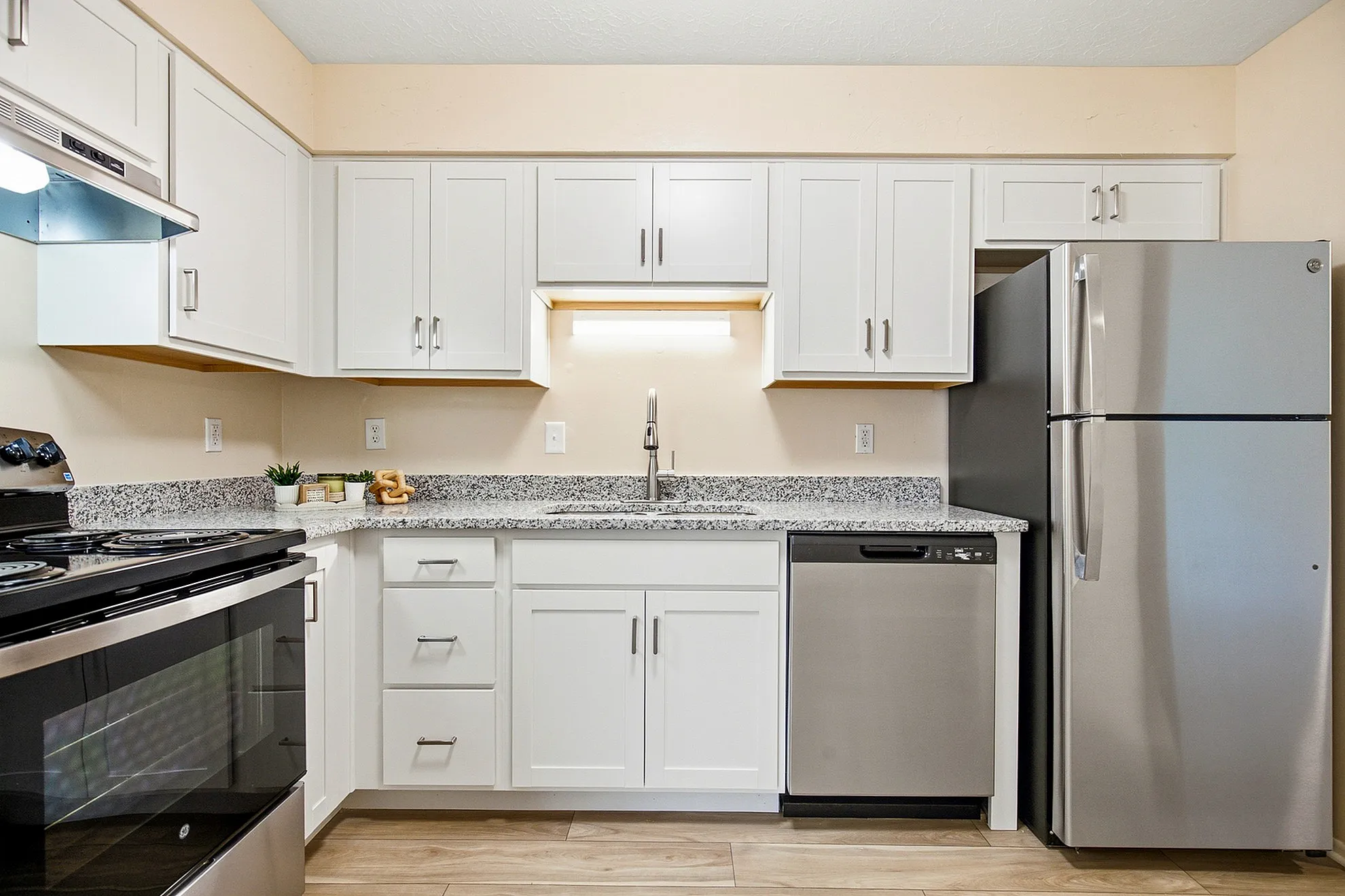 Modern kitchen with sleek stainless steel appliances, granite countertops, and elegant white cabinetry.