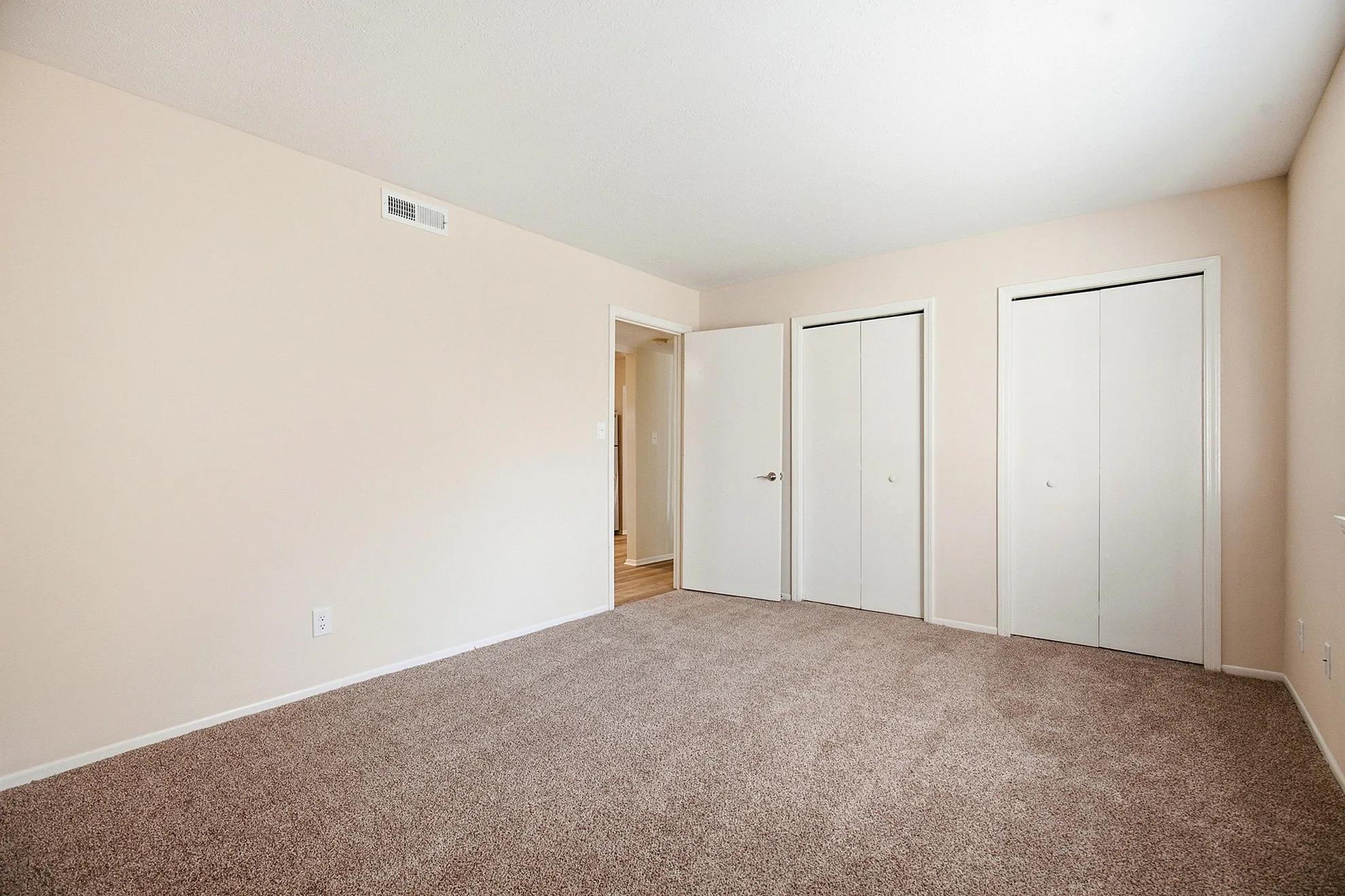 Spacious and inviting bedroom with plush carpet and dual closets, perfect for creating a cozy retreat.