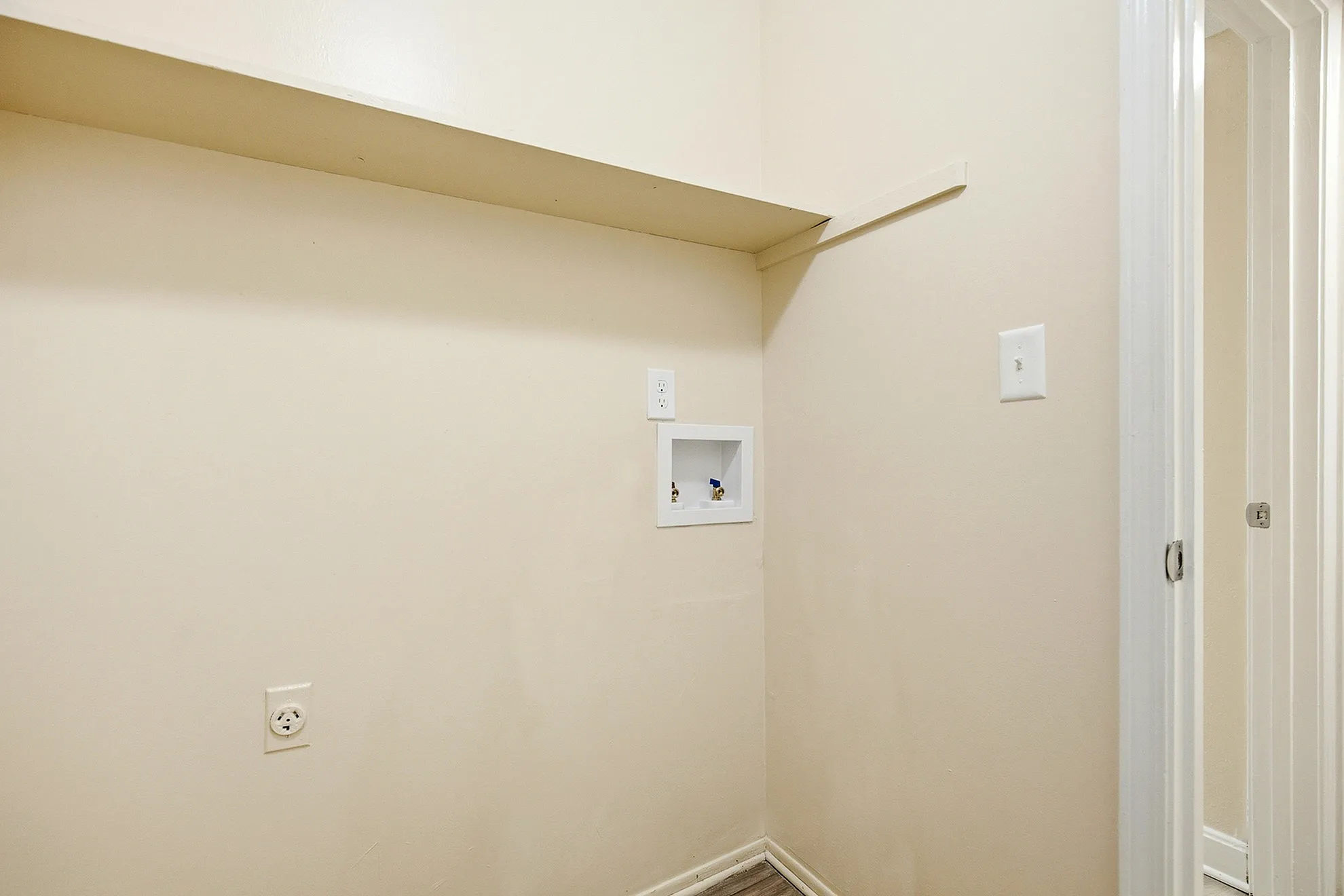 Bright laundry nook with hookups, featuring a convenient electrical outlet and streamlined design.