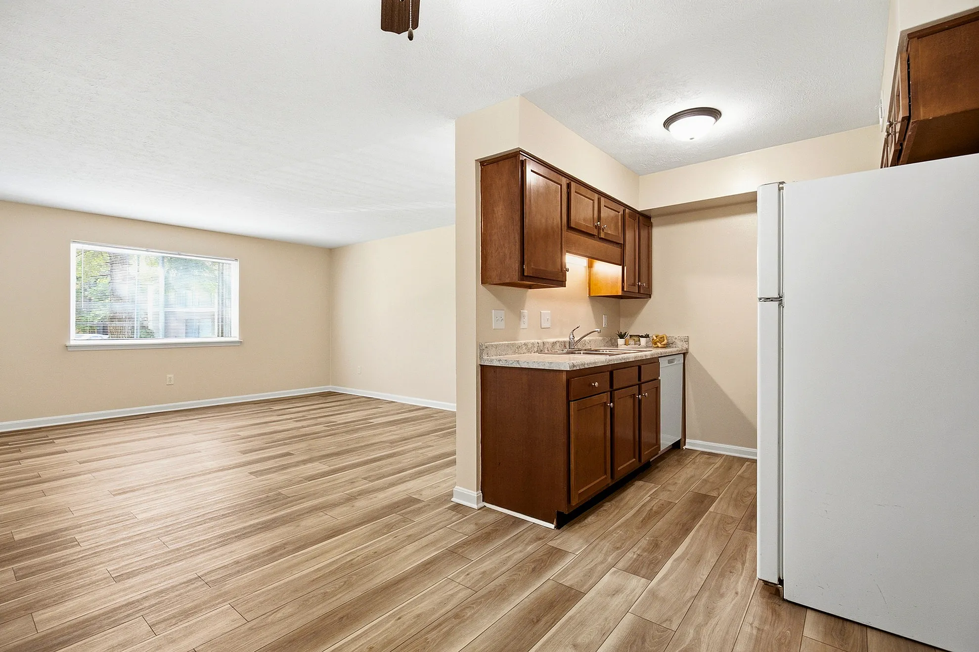 Bright and spacious living area with modern wood flooring, featuring a cozy kitchen with sleek cabinetry and ample natural light.