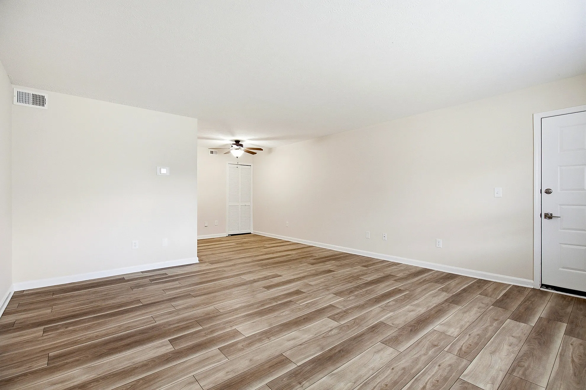 Bright and inviting living room with stylish wood flooring, ceiling fan, and ample natural light.