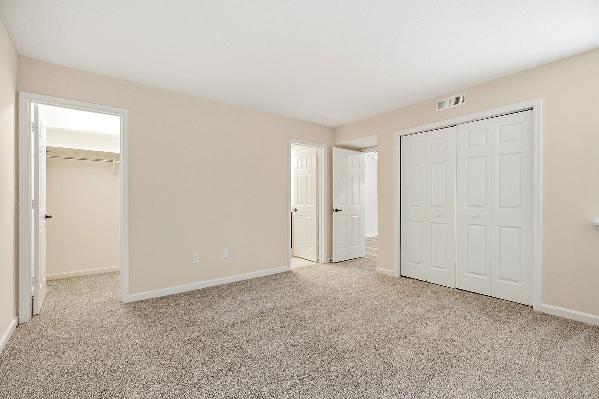Spacious bedroom with plush carpet, featuring dual closets and ample natural light.