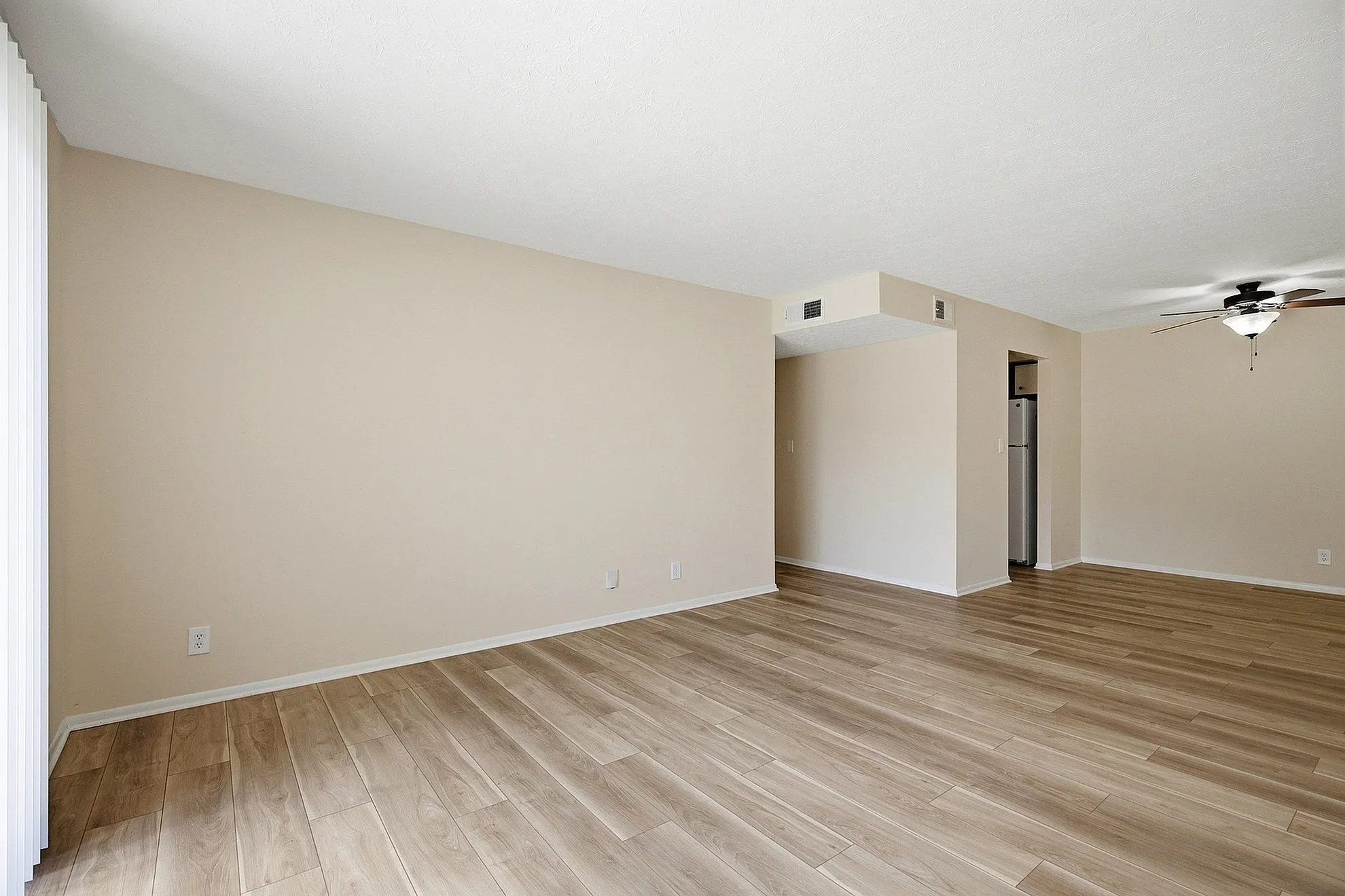 Spacious open-plan living area with stylish wooden flooring and modern ceiling fan, perfect for a bright and airy home atmosphere.