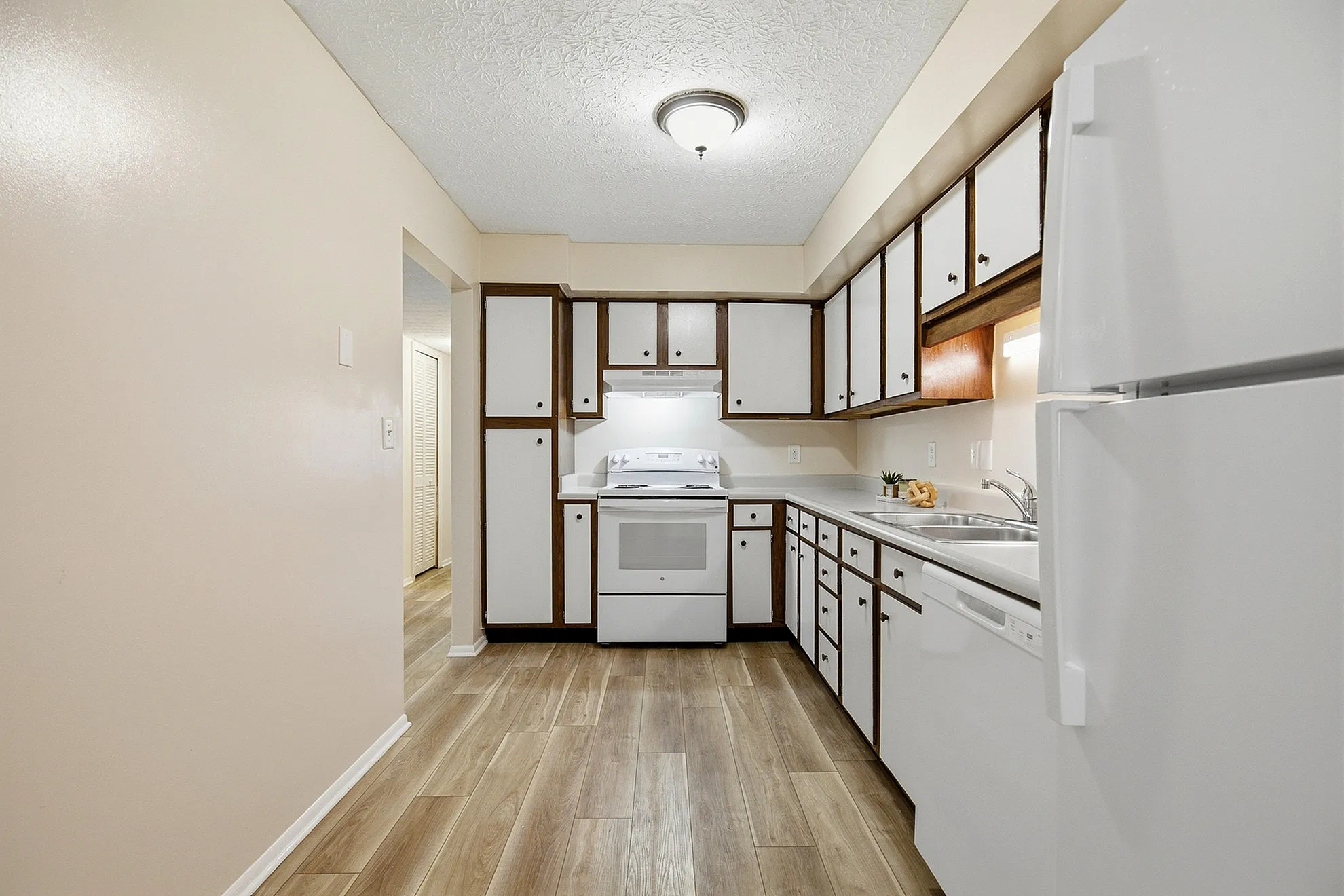 Charming kitchen with sleek white cabinets, modern appliances, and stylish wood flooring, perfect for culinary creativity.