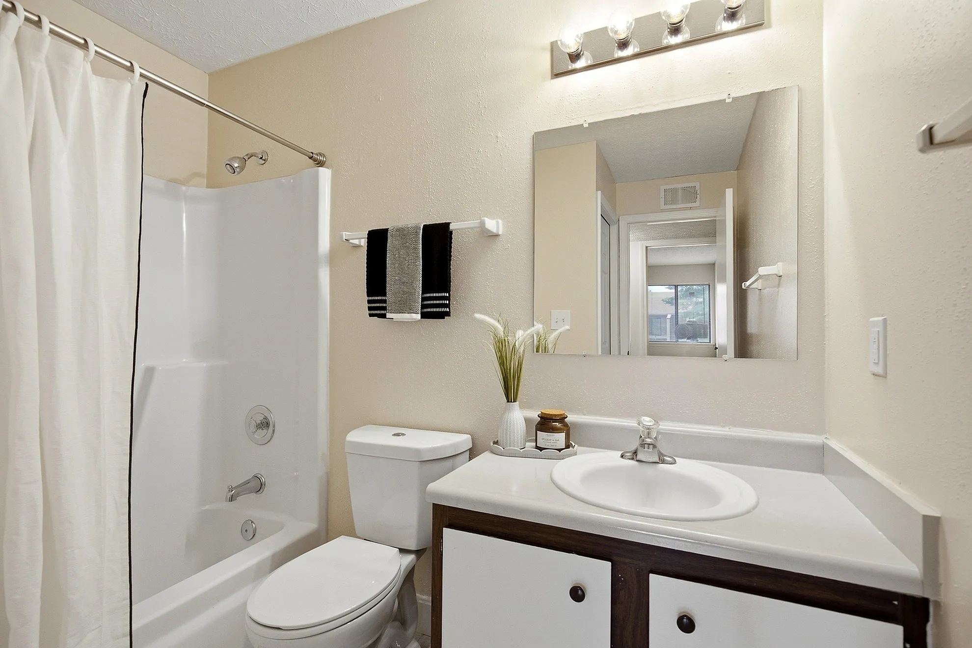 Bright and modern bathroom featuring a sleek vanity, elegant lighting, and a full bathtub with shower.
