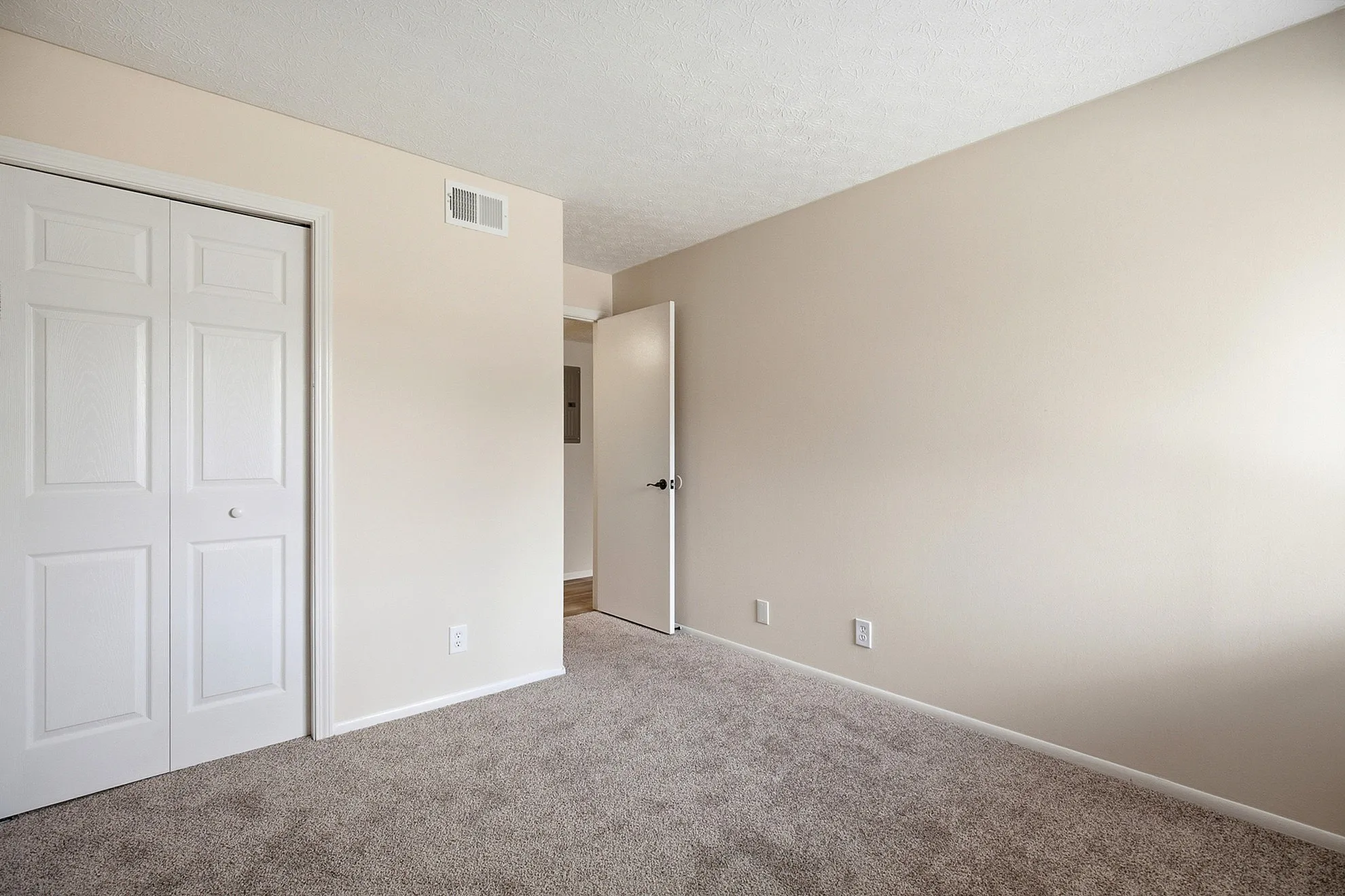 Bright, spacious bedroom featuring plush carpet and neutral walls, perfect for a cozy, personalized retreat.